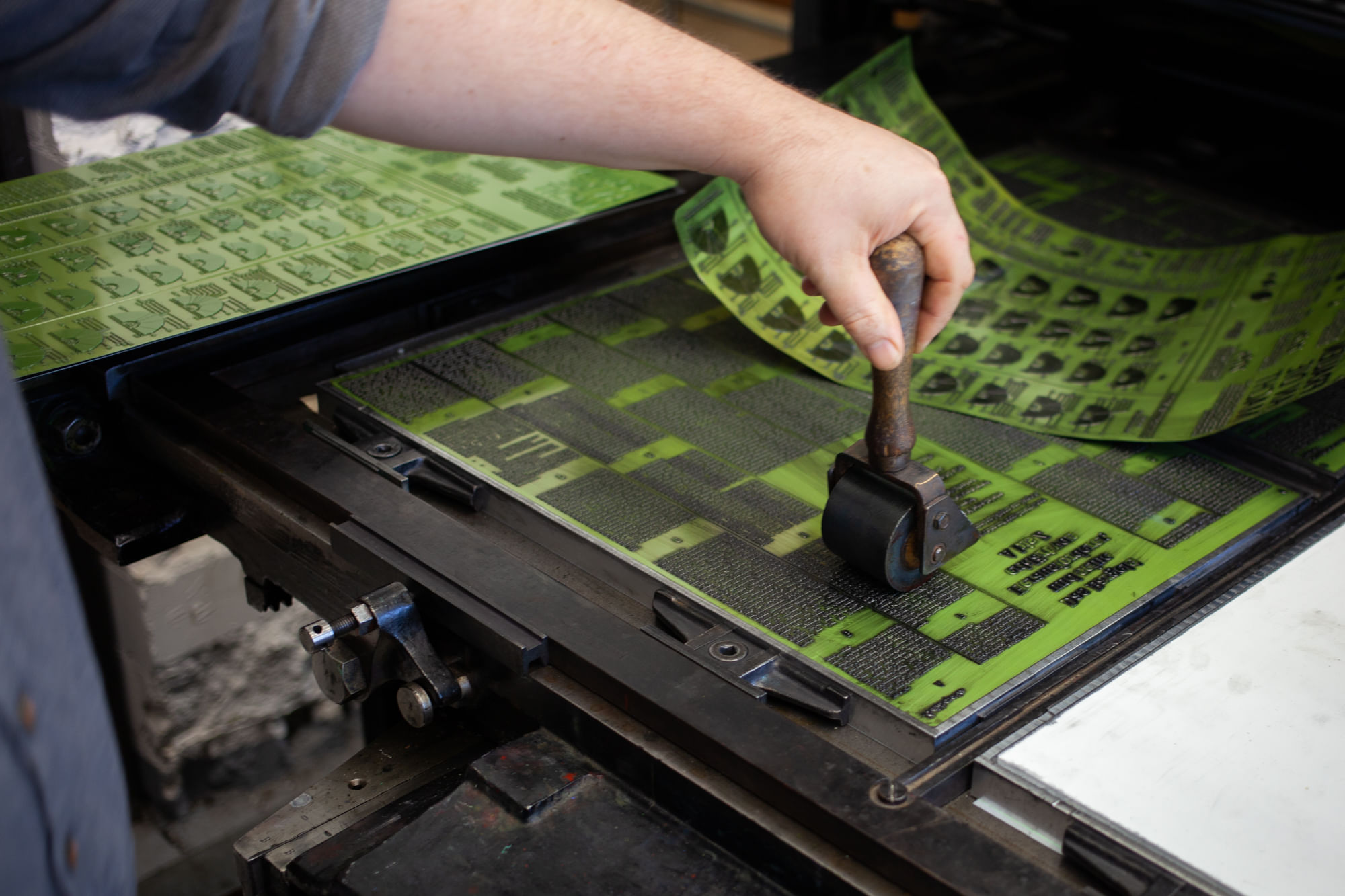 Wenn die meterlange, schwere Rolle die Buchstaben mit Farbe beschichtet (hier durch eine kleine Rolle angedeutet), übt sie enormen Druck auf die Nyloprint-Platten aus.
