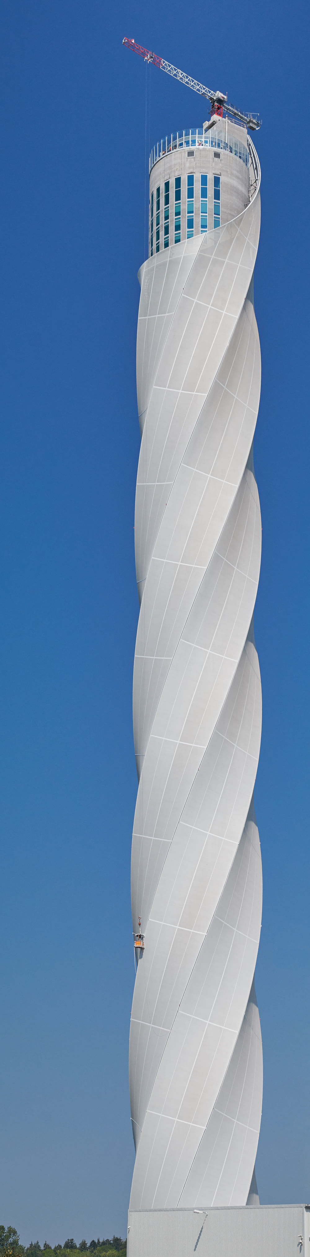 Ein nicht enden wollendes Foto, hochkant, zeigt einen sich in den Himmel windenden Turm mit Kran auf der höchsten Stelle des Turms