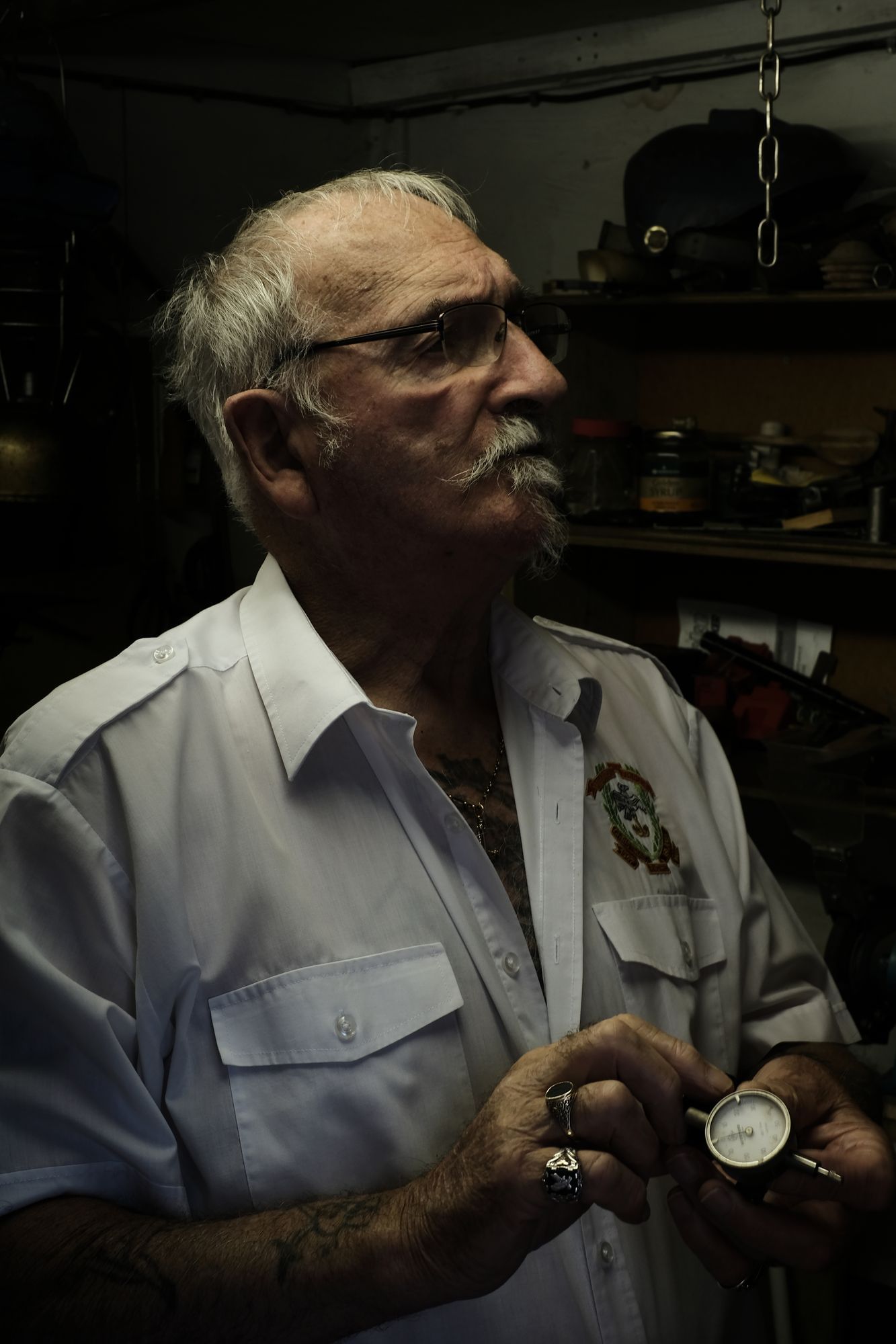 Douglas Hern, ein älterer Herr mit Bart und Brille, steht in seinem Zimmer zuhause und blickt auf alte Navy Utensilien, dabei hält er eine Stoppuhr in der Hand. 