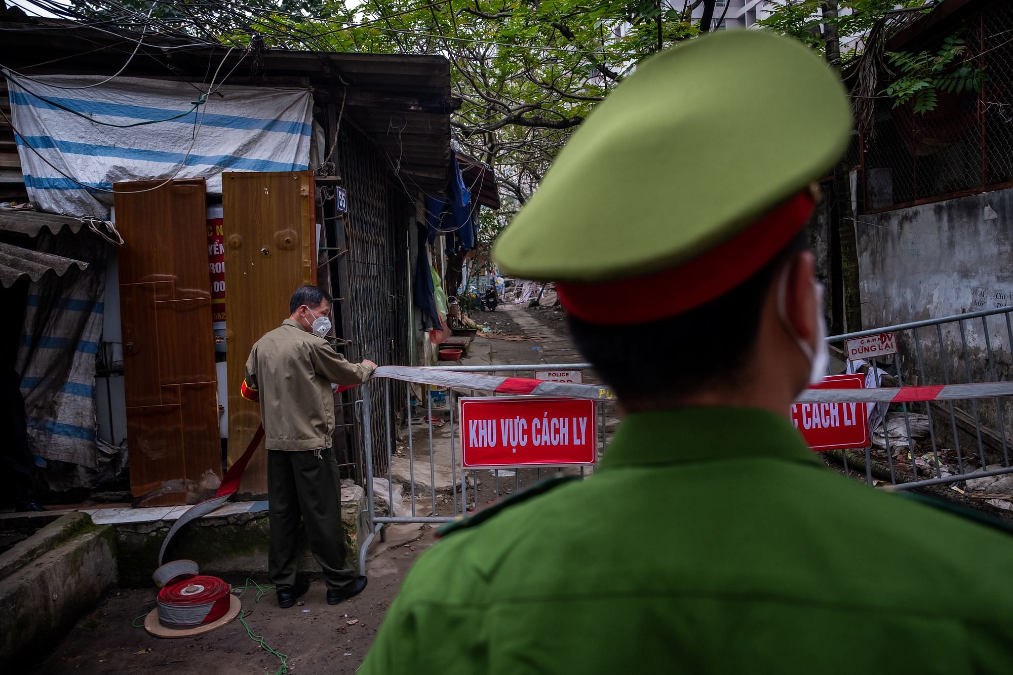 Unscharfer Rücken eines Polizisten vor der Szene eines abgesperrten Marktes in der vietnamesischen Hauptstadt Hanoi