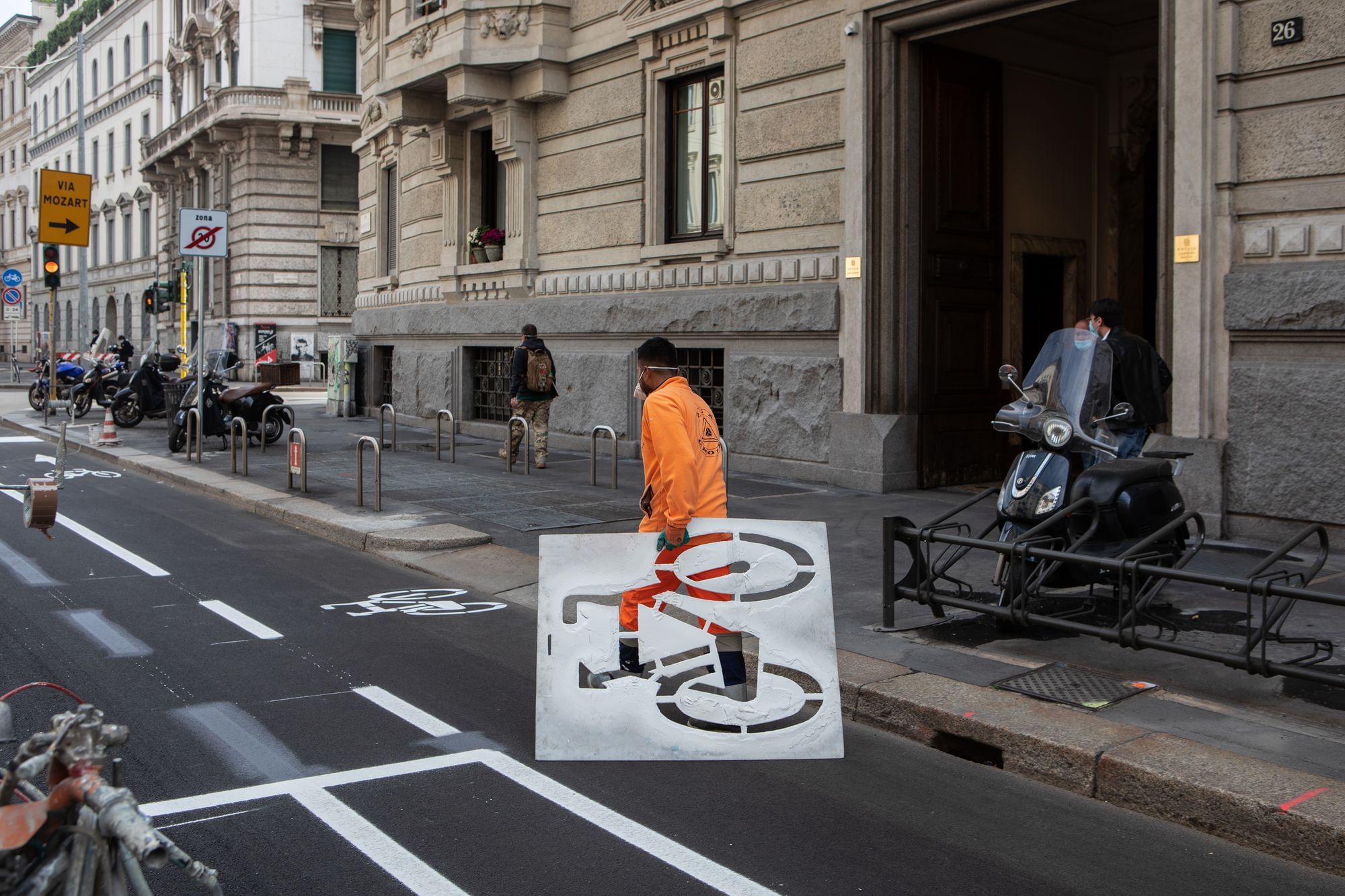 Ein Mann trägt eine Fahrrad-Pappschablone, während er daran arbeitet, einen neuen Fahrradweg zu streichen.