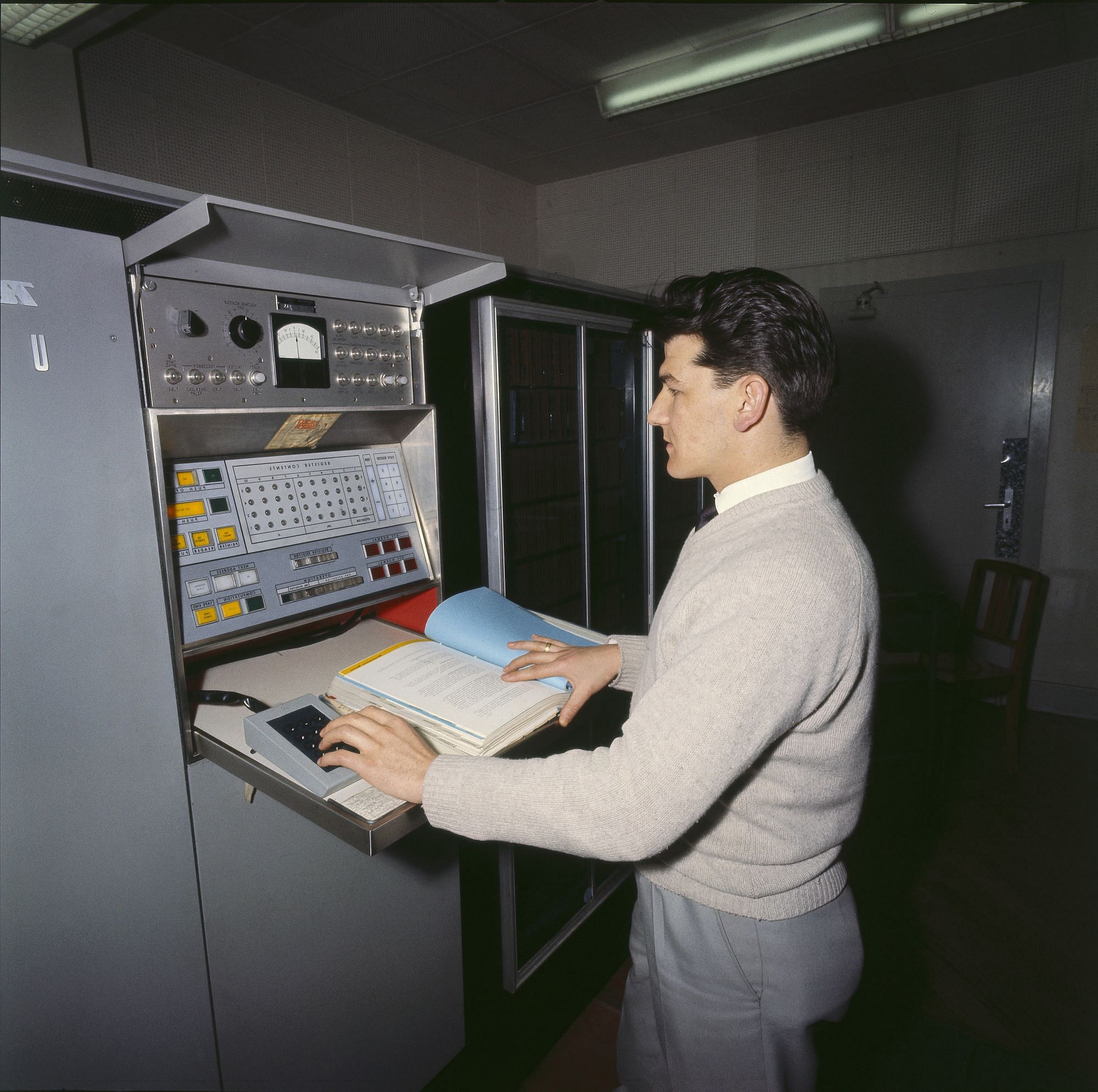 Ein Mann steht vor einer Datenverarbeitungsmaschine aus den 60er Jahren.