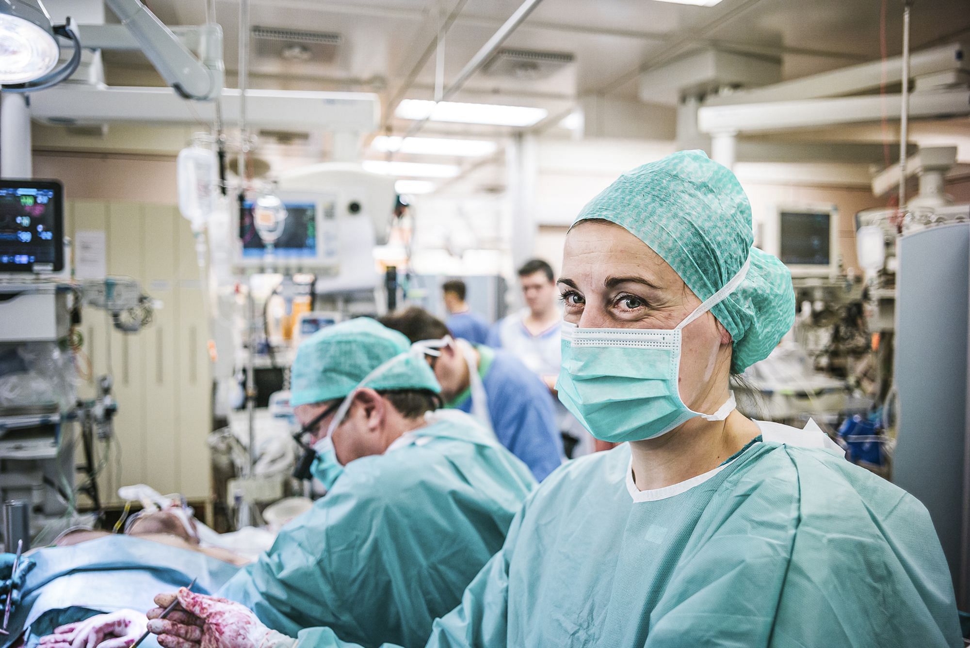 Eine weiblich gelesene OP-Pflegekraft im Operationsraum und entsprechend angekleidet mit Mundschutz.