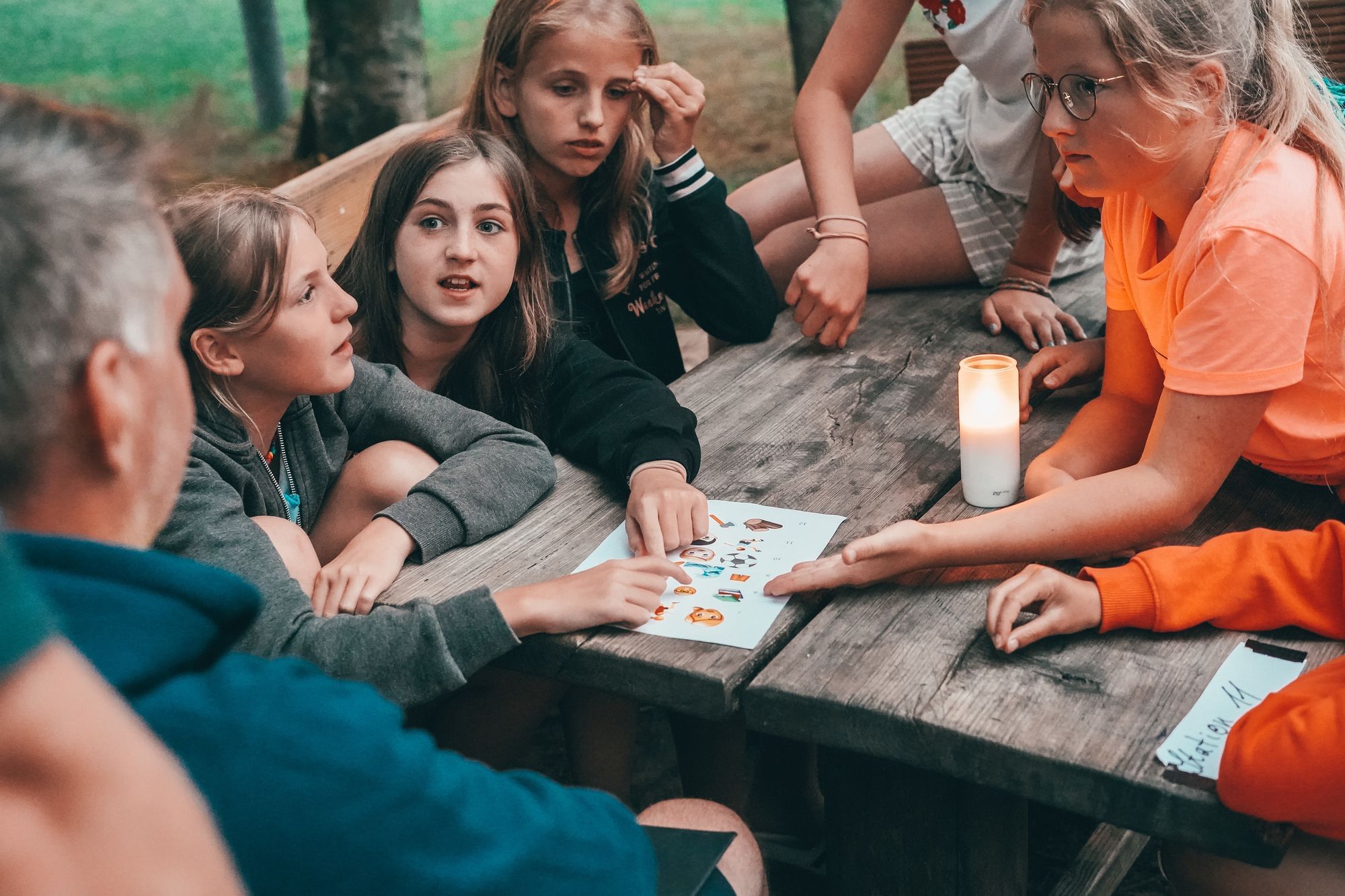 Eine Gruppe von Mädchen im Alter von 11 Jahren sitzt um einen Tisch herum und löst ein Rätsel. 