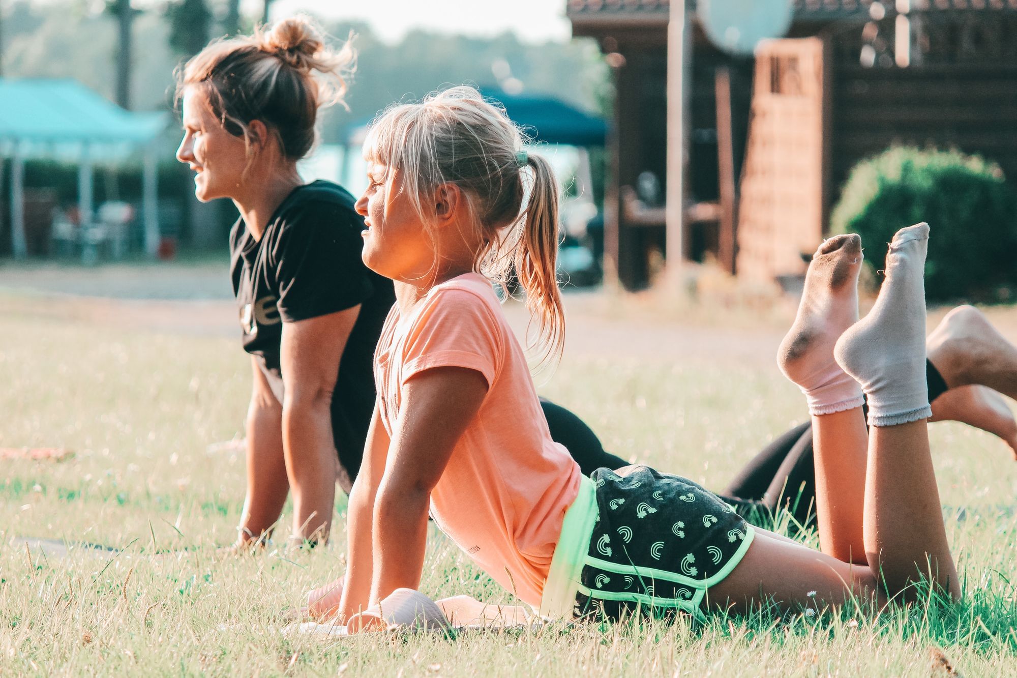 Ein Mädchen und eine Betreuerin machen Yoga in der Abendsonne.