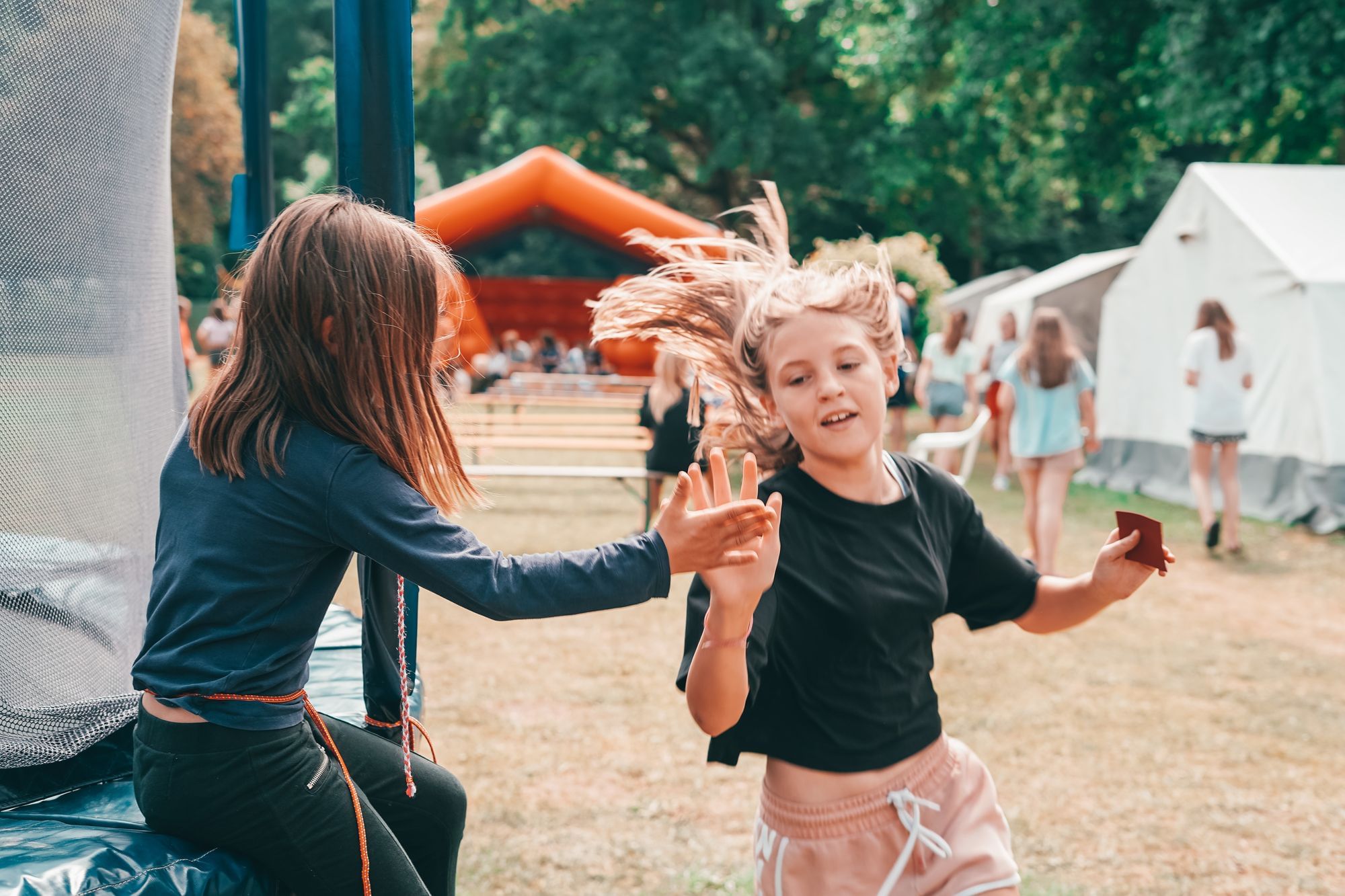 Ein elfjähriges Mädchen macht beim Biathlon mit und wird beim Laufen von einem 7-jährigen Mädchen abgeklatscht. 