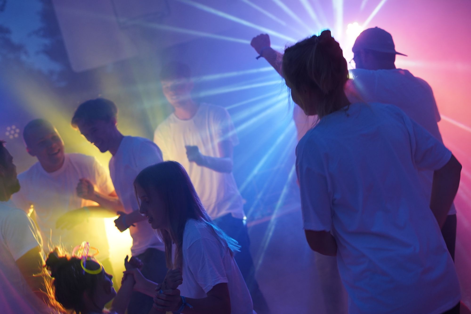 Ein Gruppenbild während der Open-Air-Disco. Laserlicht strahlt in die Kamera, man sieht die Umrisse von tanzenden Menschen.