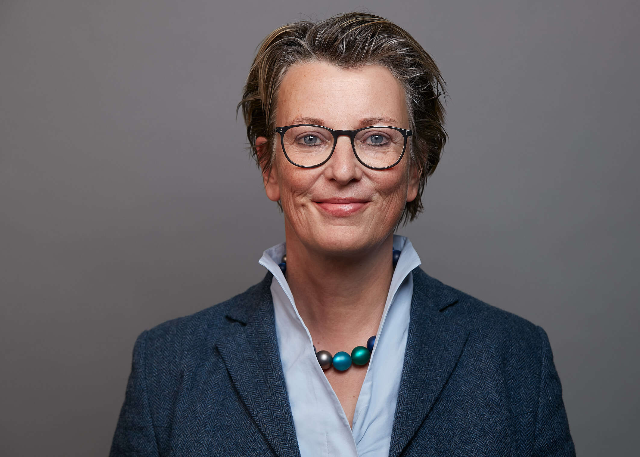 Eine Frau in moderner Kleidung und Brille.