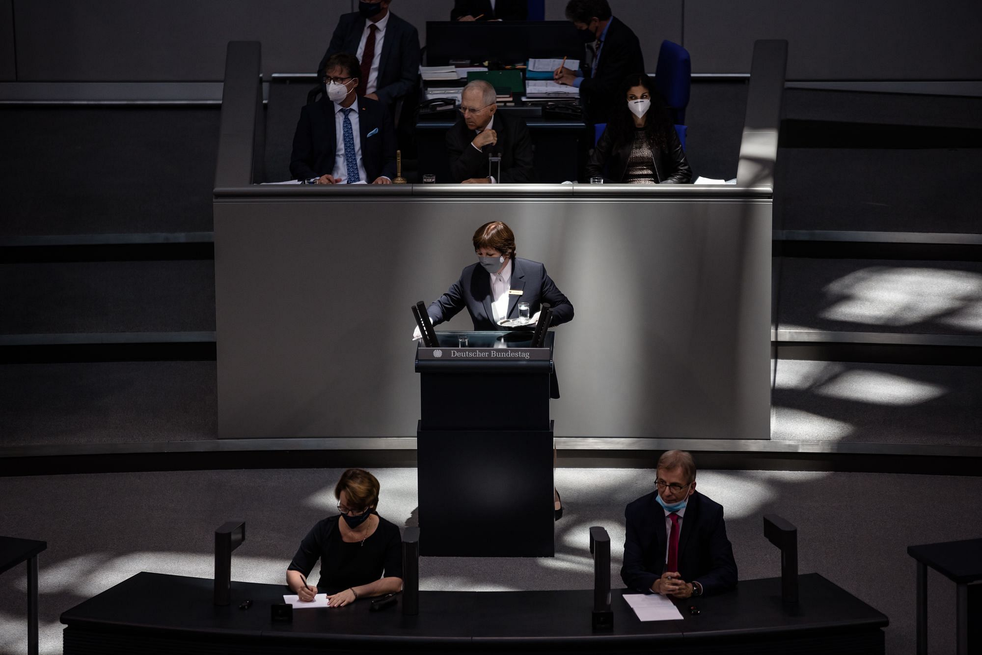 Eine Saaldienerin desinfiziert das Redner:innenpult im Plenarsaal des Bundestages