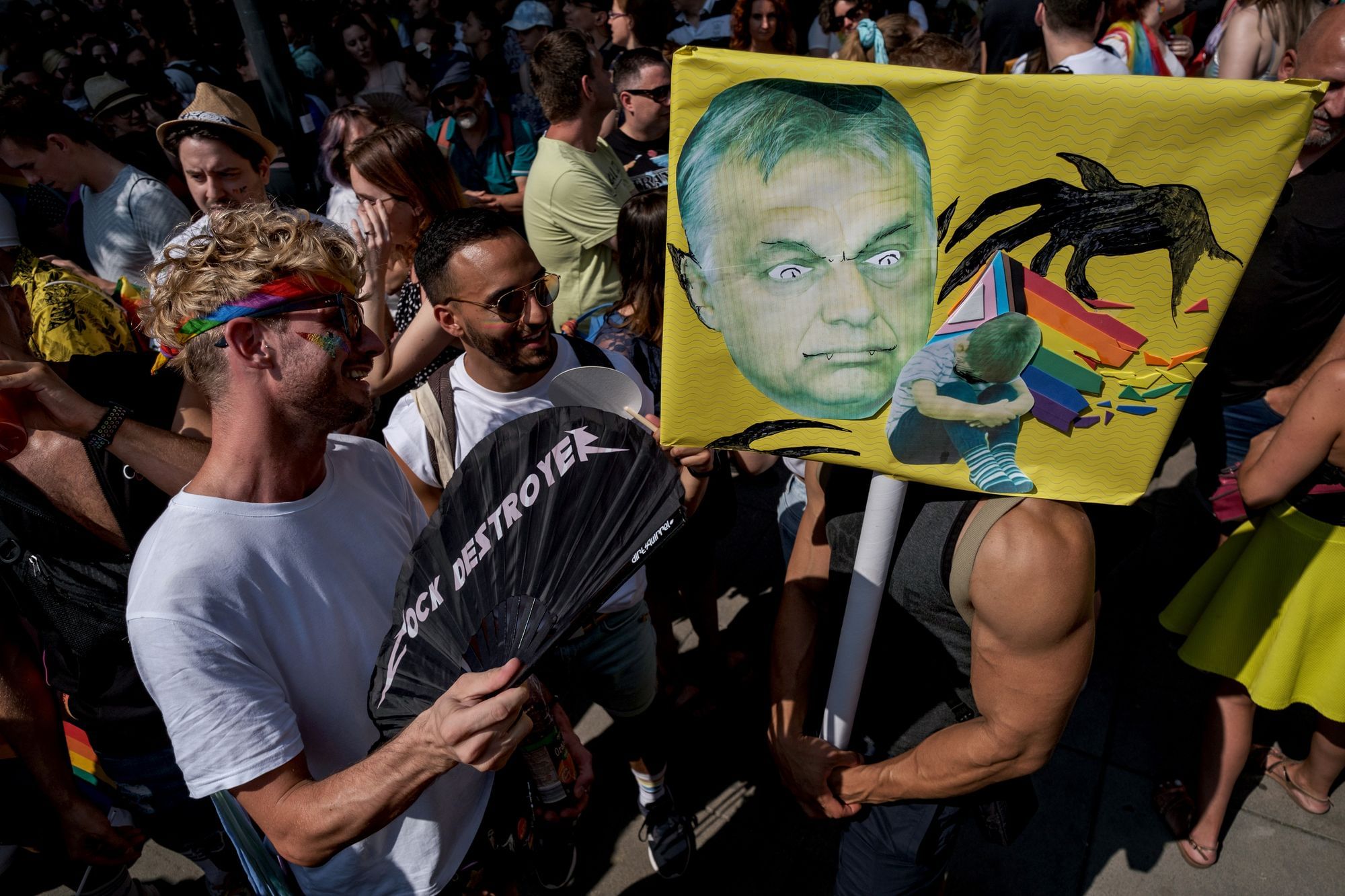 Demonstrierende auf der Gay Pride in Budapest halten ein Schild mit Victor Orban als Dämon hoch, der LGBTQIA+ Kinder bedroht.