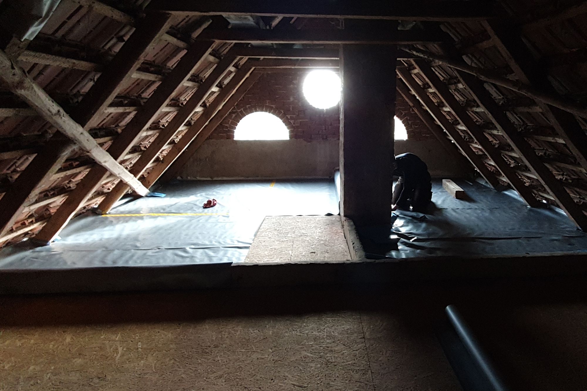 Der Dachboden des Hauses, mit zwei halbrunden und einem runden Fenster welches das Licht hereinlässt.