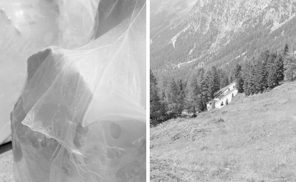 Vertikaler Diptych, schwarz weiß; links- ein in Plastik verpackter Käse, das Plastik erweckt den Eindruck von Spinnenweben; rechts- Landschaftaufnahme, Bergab, Blick auf Serpentinen mit Motorradfahrer:innen.