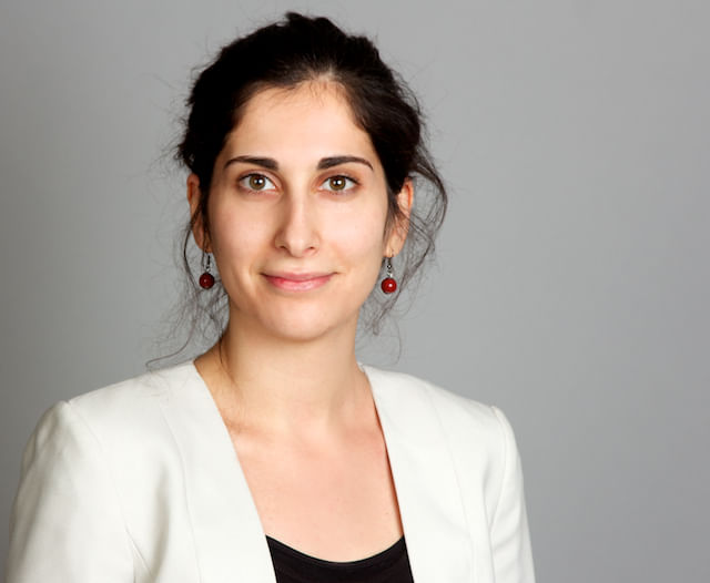 Larissa Hassoun blickt direkt in die Kamera. Sie ist ein Frau mit schwarzen Haaren, trägt unauffällige kleine Ohrringe und weißes Sacko.