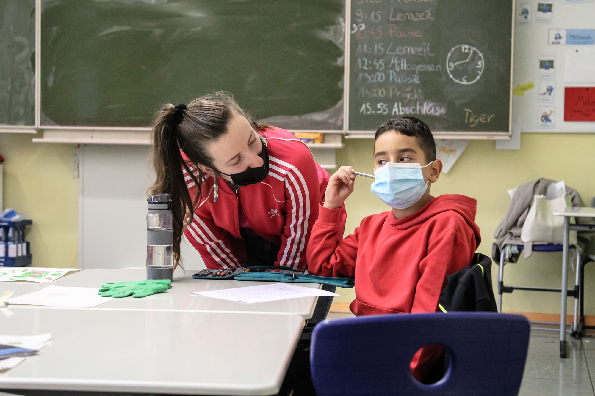 Laura Mydlowksi bückt sich zu einem Jungen herunter und reden mit ihm.