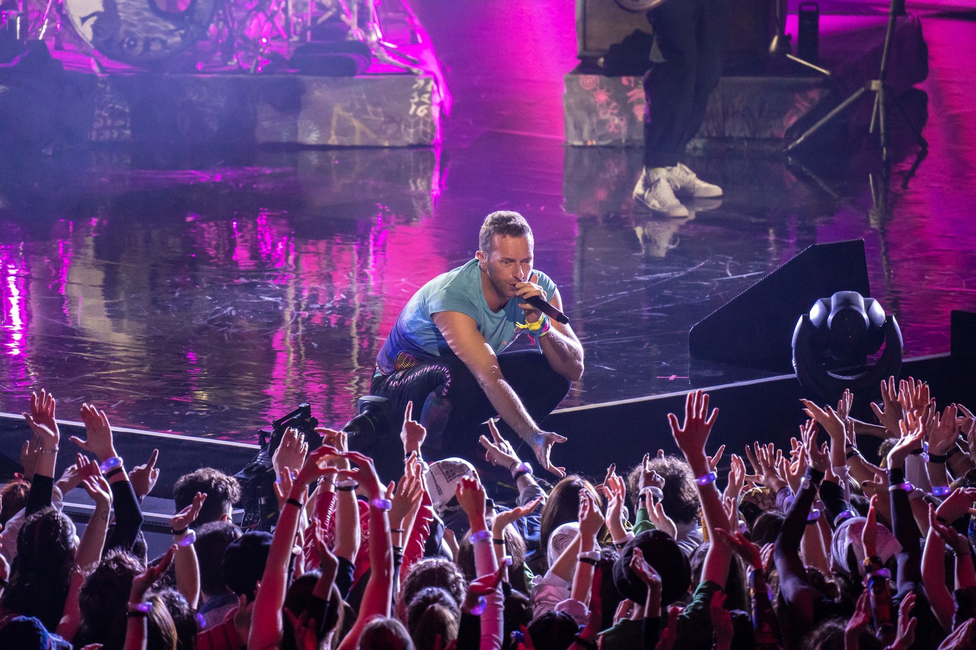 Chris Martin hockt am Rande der Bühne und sucht den Kontakt zu ausgelassenen Fans.