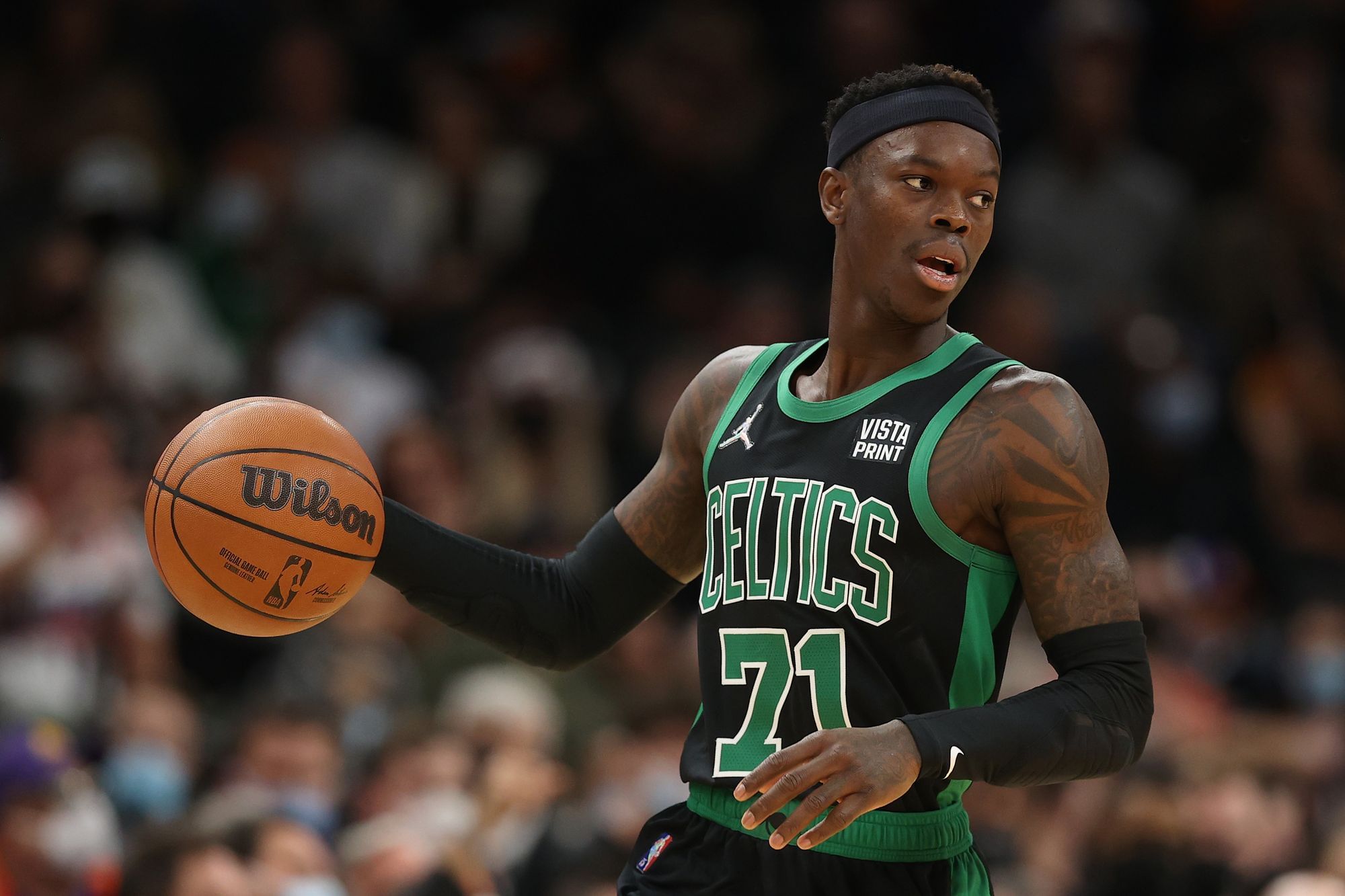 Dennis Schröder, eine schwarze männlich gelesene Person mit kurzen Haaren und athletischem Auftreten, am Ball, bereit zum passen.