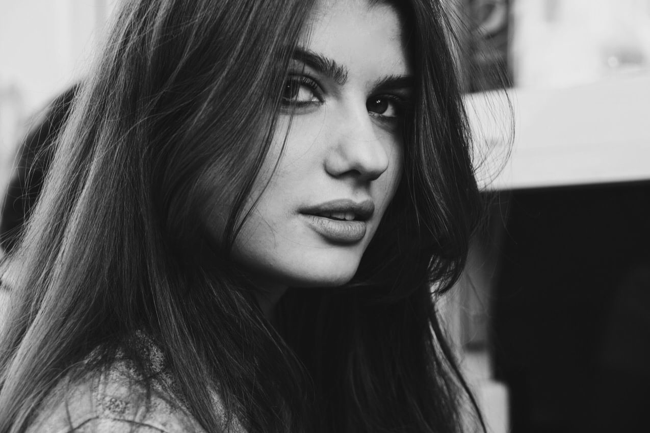 Eine schwarz-weiß Fotografie einer jungen Frau mit langen, braunen Haaren.