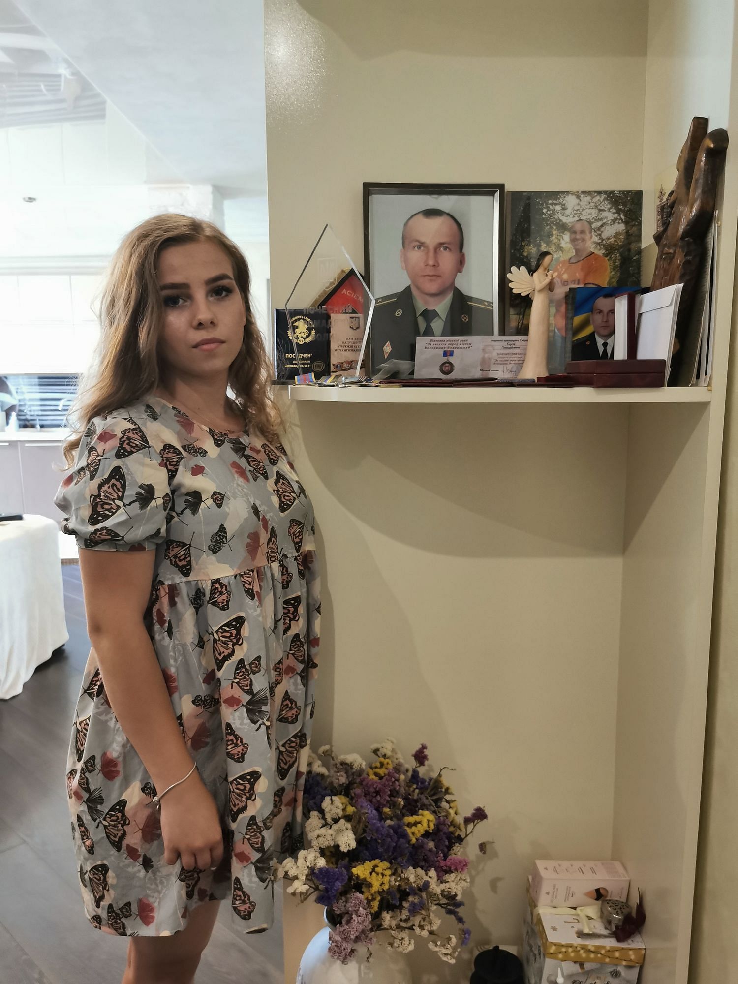 Eine Frau steht vor dem Soldaten-Foto ihres toten Mannes.