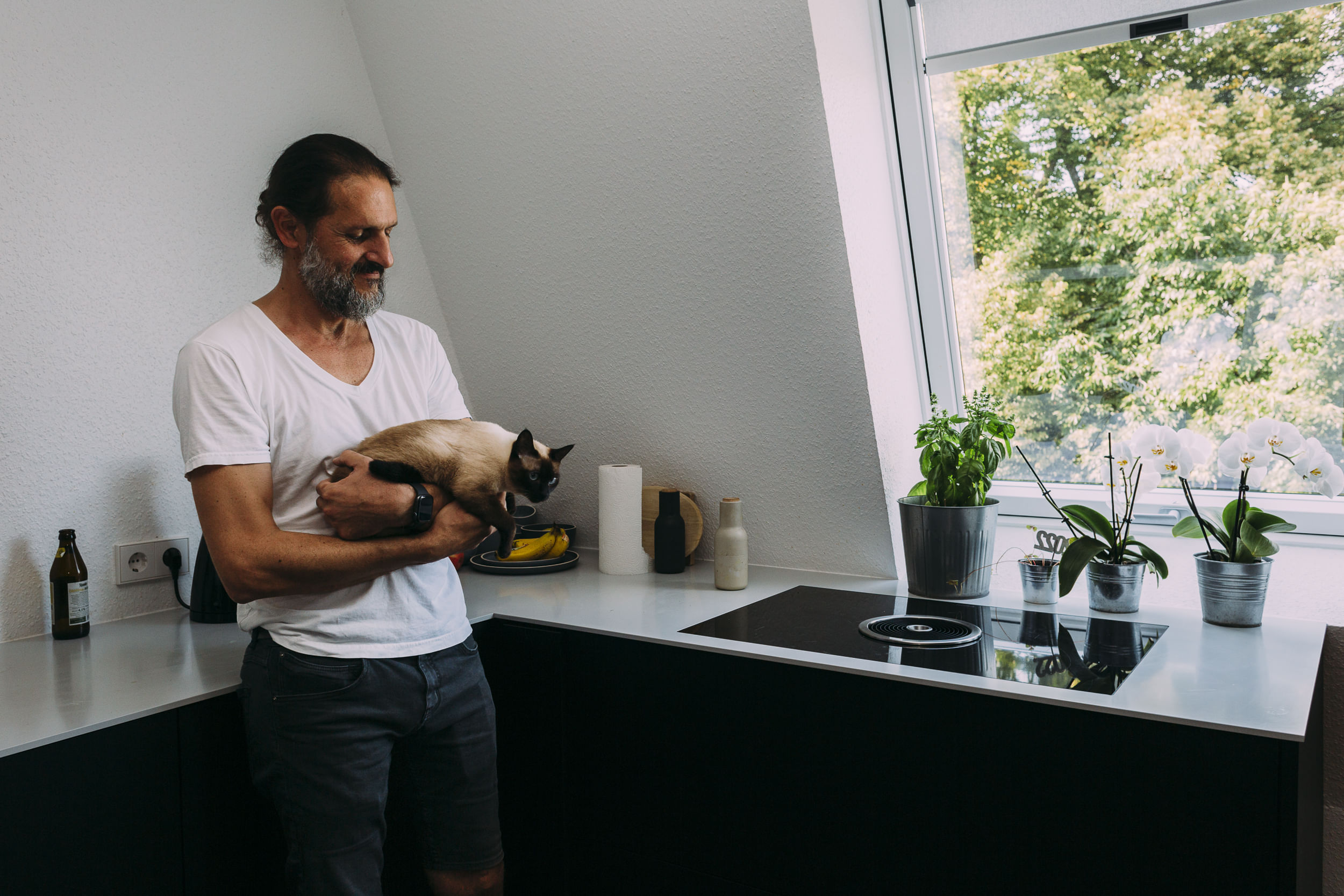 Saad steht in seiner Küche, er hält seine Katze auf dem Arm.