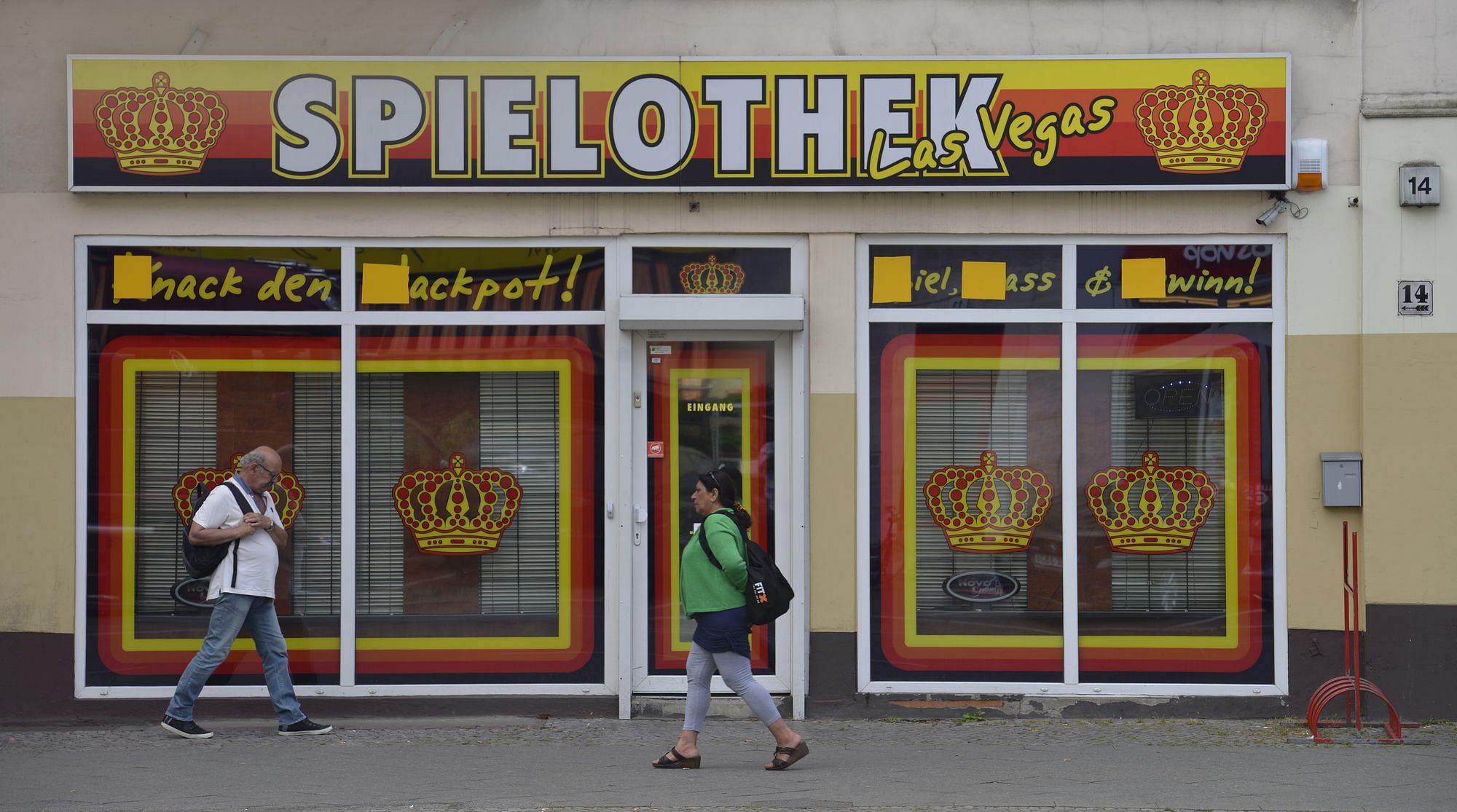 Die Ladenfront einer Spielothek. Die Schaufenster sind mit Rollos versehen, man kann nicht hineinblicken. Ein großes Plastikschild hängt darüber, auf dem "Spielothek Las Vegas" steht.
