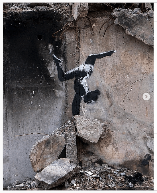 Ein Graffito auf grauen Trümmern zeigt ei Mädchen, das Handstand macht.