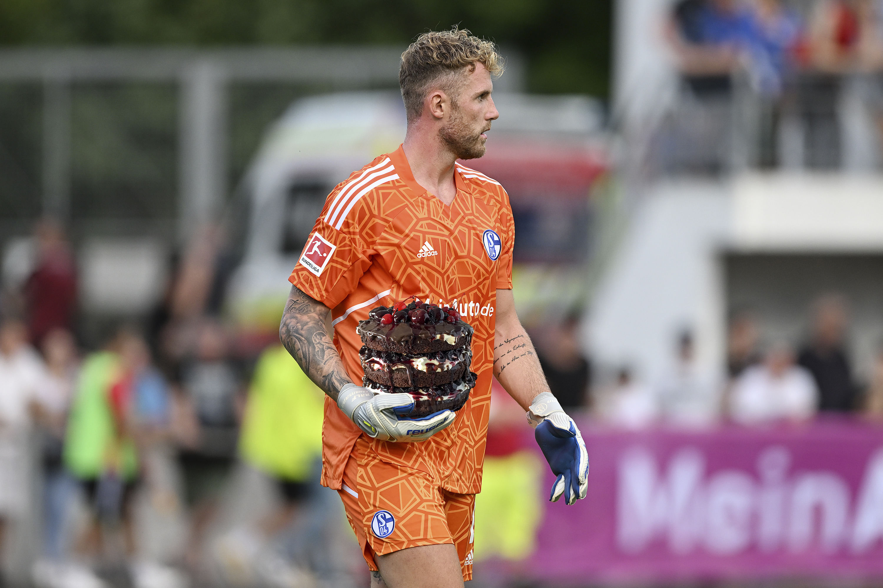 Man sieht einen Fußballer, der Torwart ist, und statt eines Fußballs eine Torte in der Hand hält.