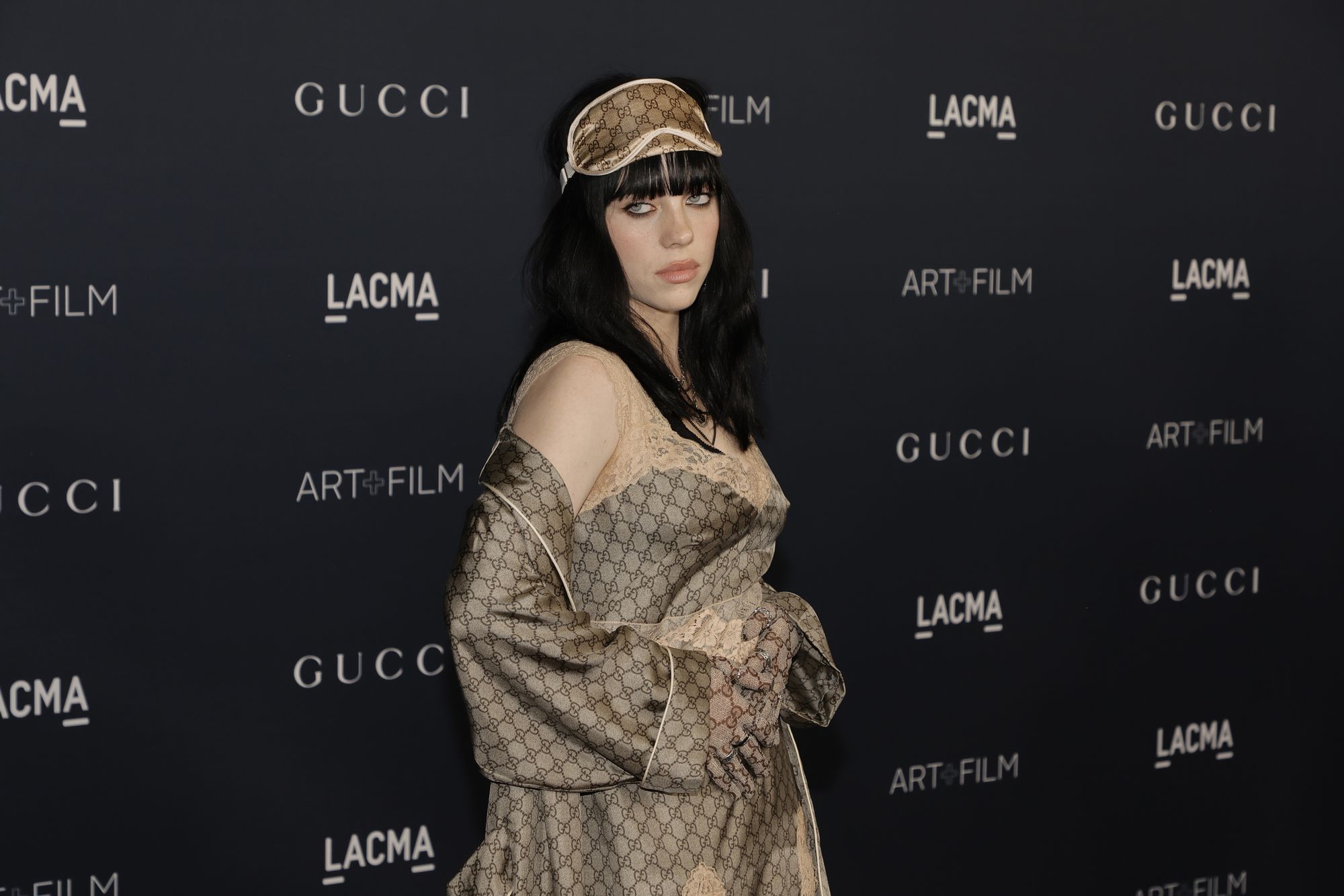 Man sieht Billie Eilish vor einer Leinwand stehen.