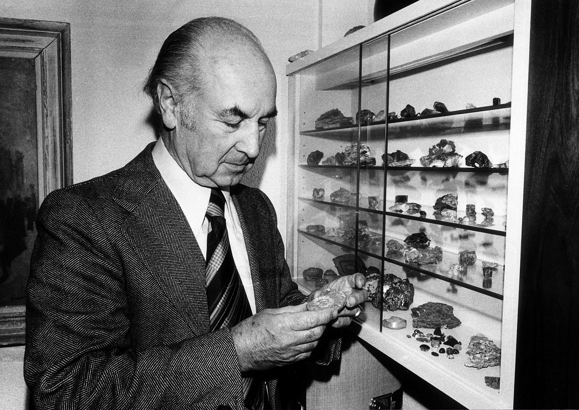 Wir sehen einen älteren Mann, der einen Stein in der Hand hält und begutachtet.
