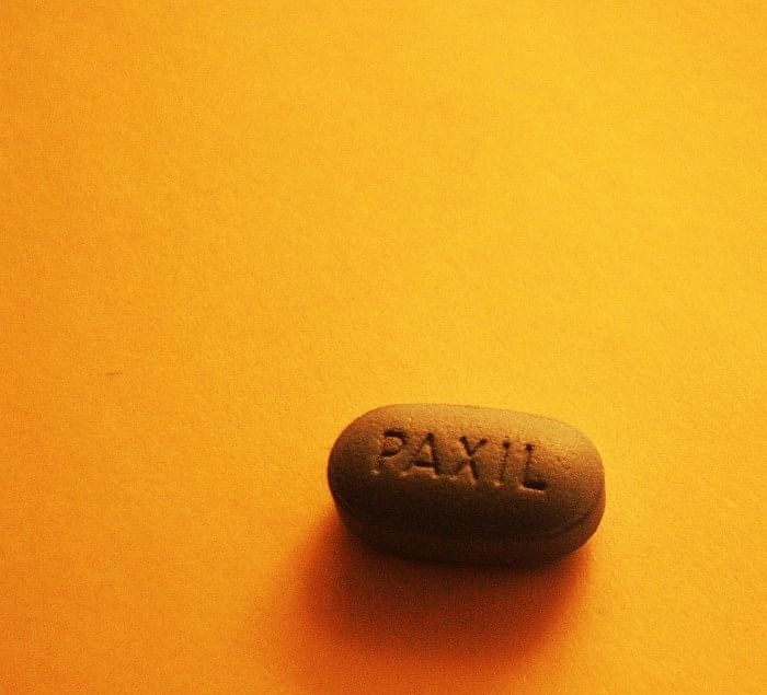 Wir sehen eine braune Tablette Paxil auf einem gelben Hintergrund.