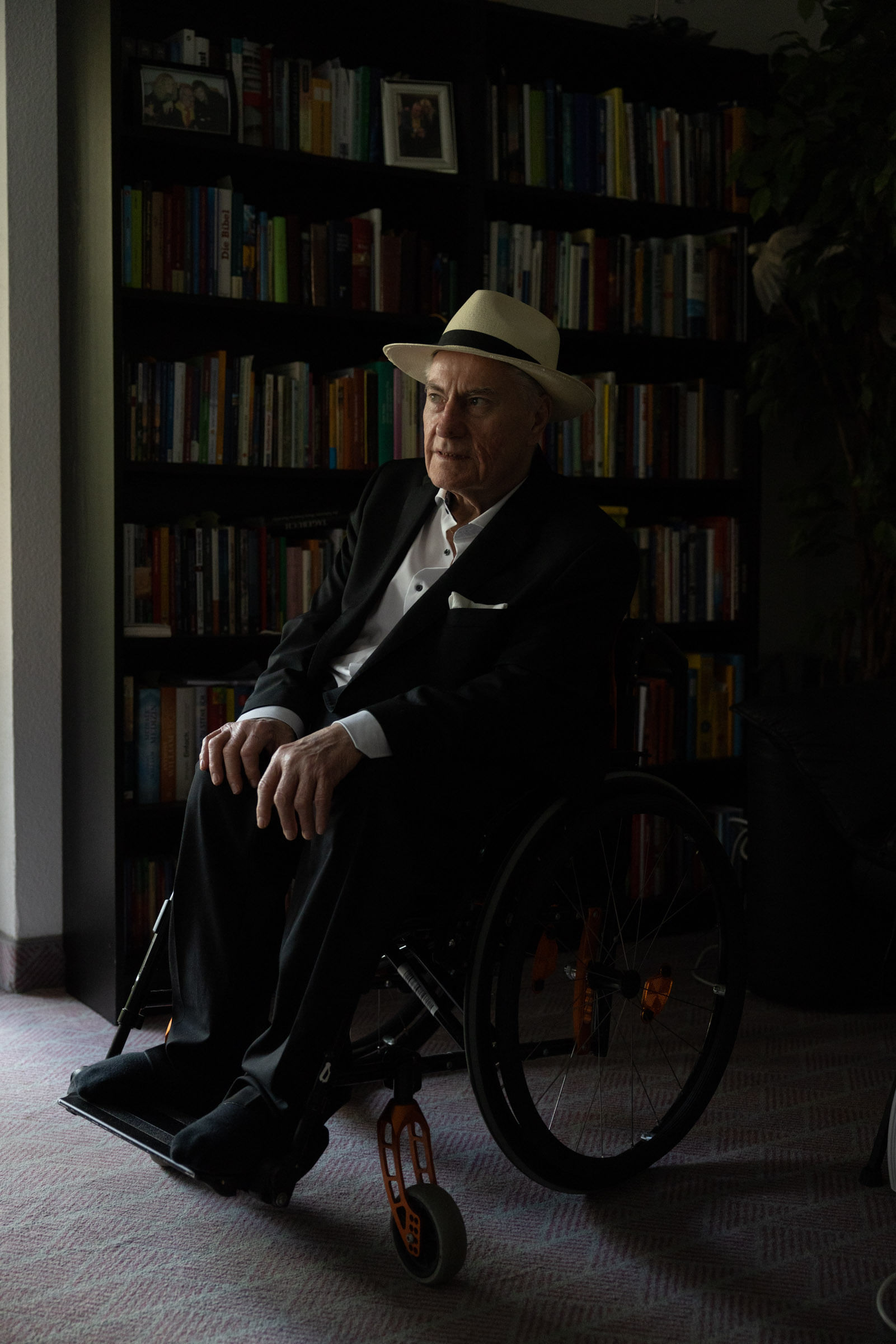 Josef Müller sitzt im Rollstuhl vor einem Bücherregal