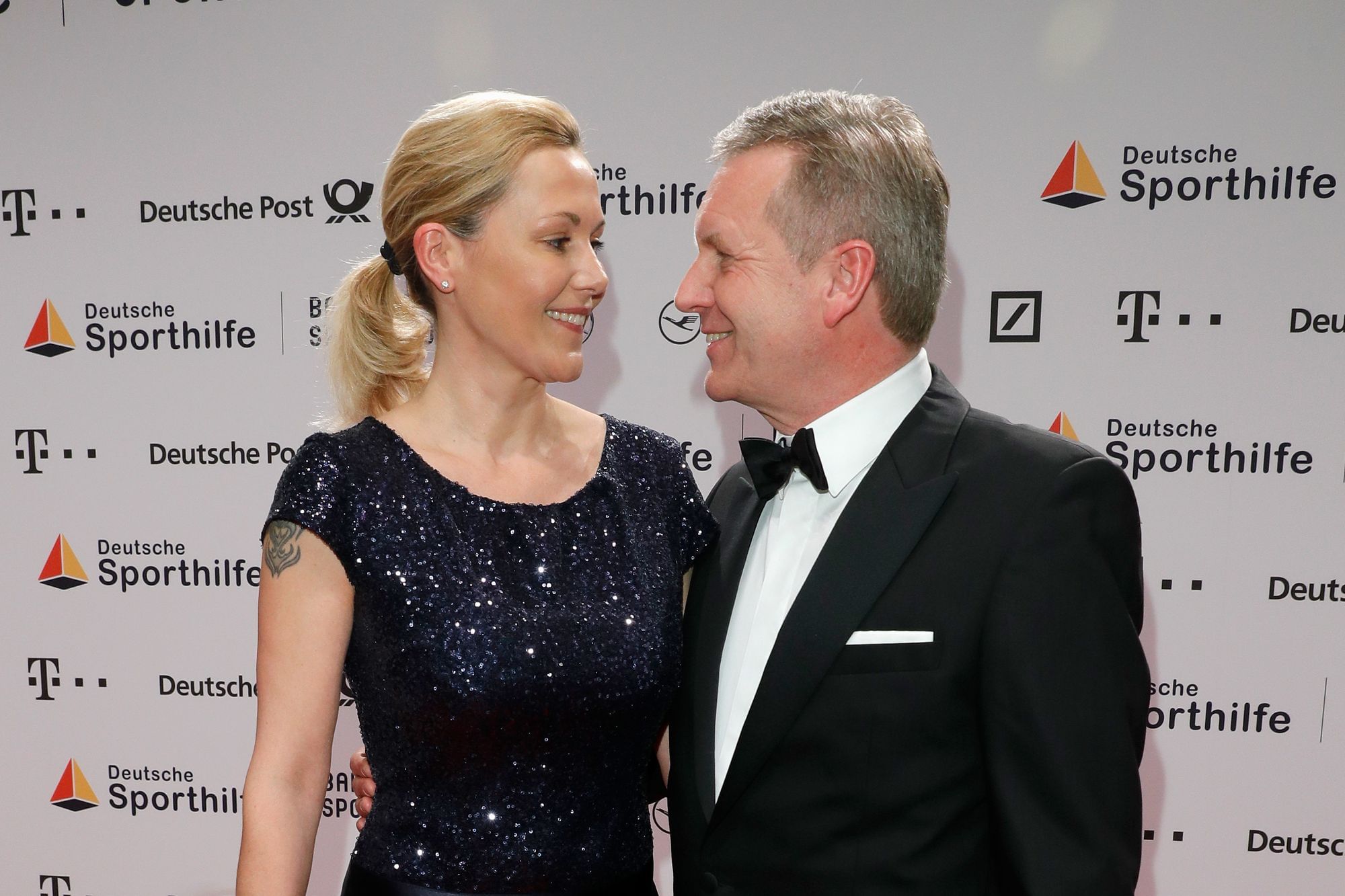 Man sieht ein Paar, das festlich gekleidet ist, sich im Arm hält und verliebt anschaut. Es sind Bettina und Christian Wulff.