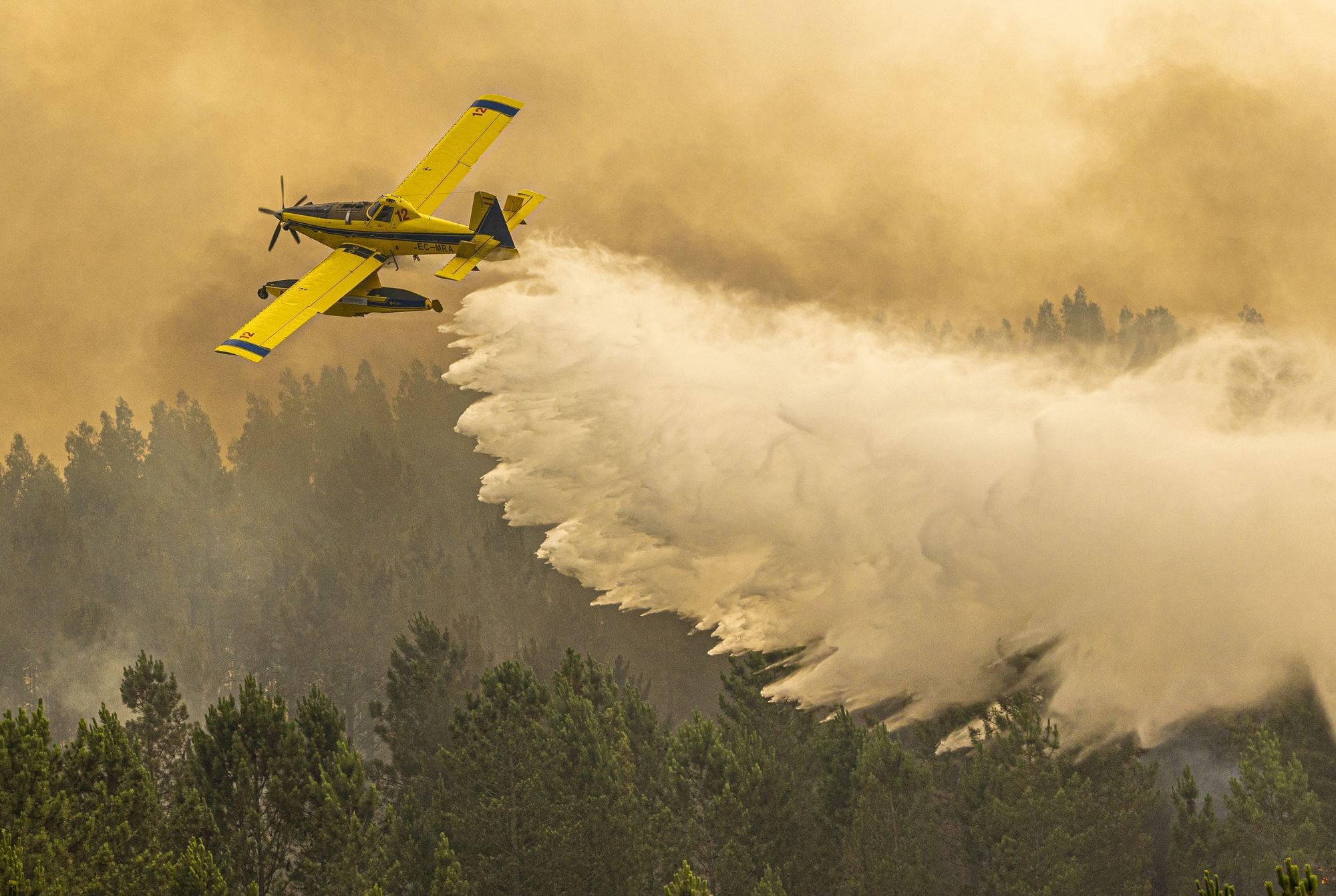Ein Air Tractor Löschflugzeug entlässt Wasser über einem Waldbrand in Portugal.