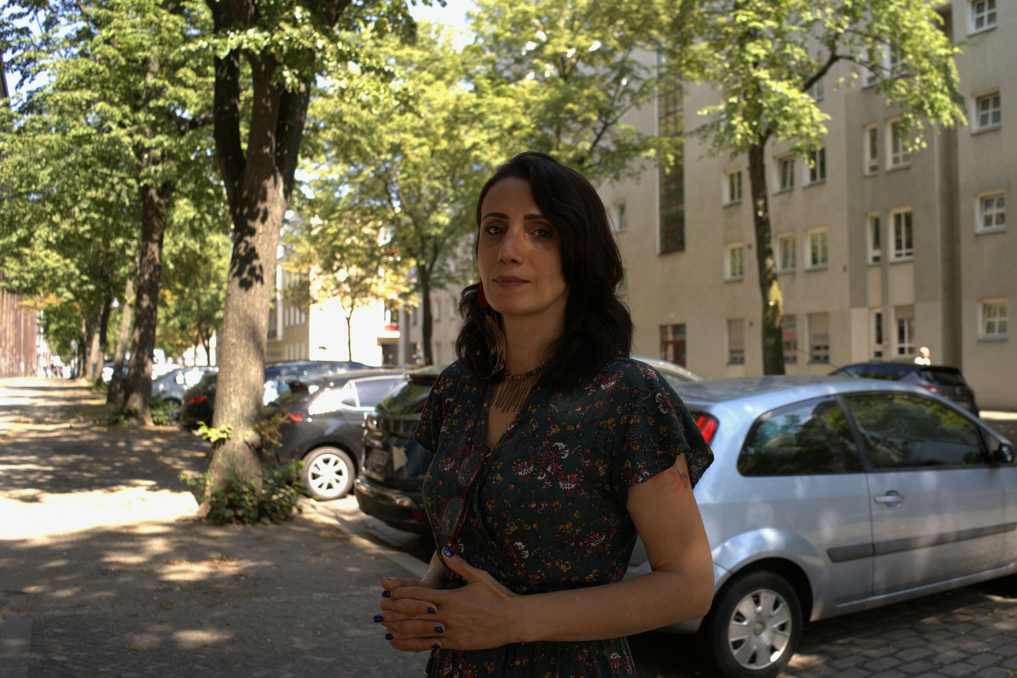 Meral Şimşek, in dunklem Kleid auf einer Kopfsteinpflaster-Straße in Berlin.