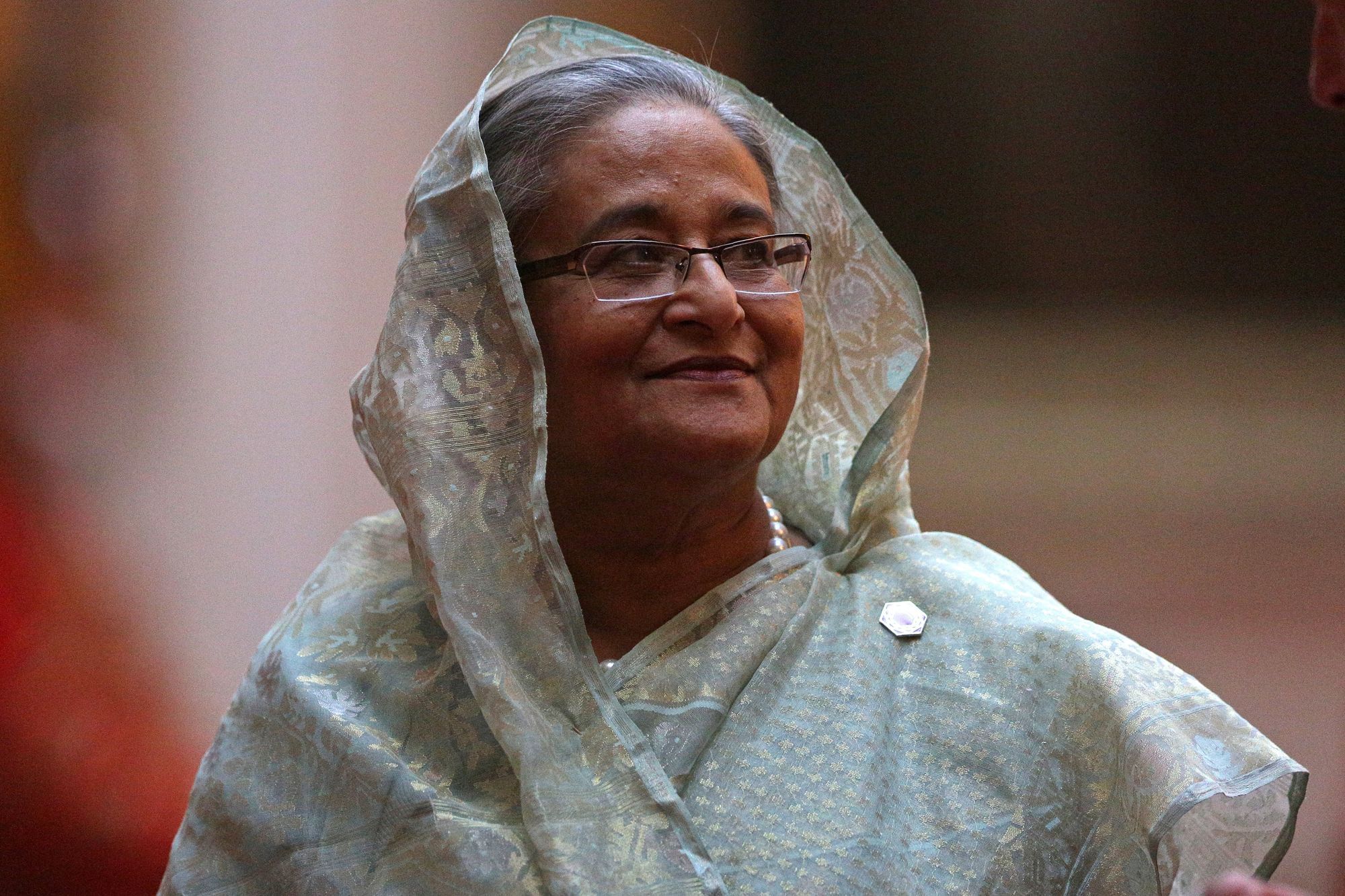 Scheich Hasina, in traditioneller bangladeschischer Kleidung, blickt lächelnd zur Seite.