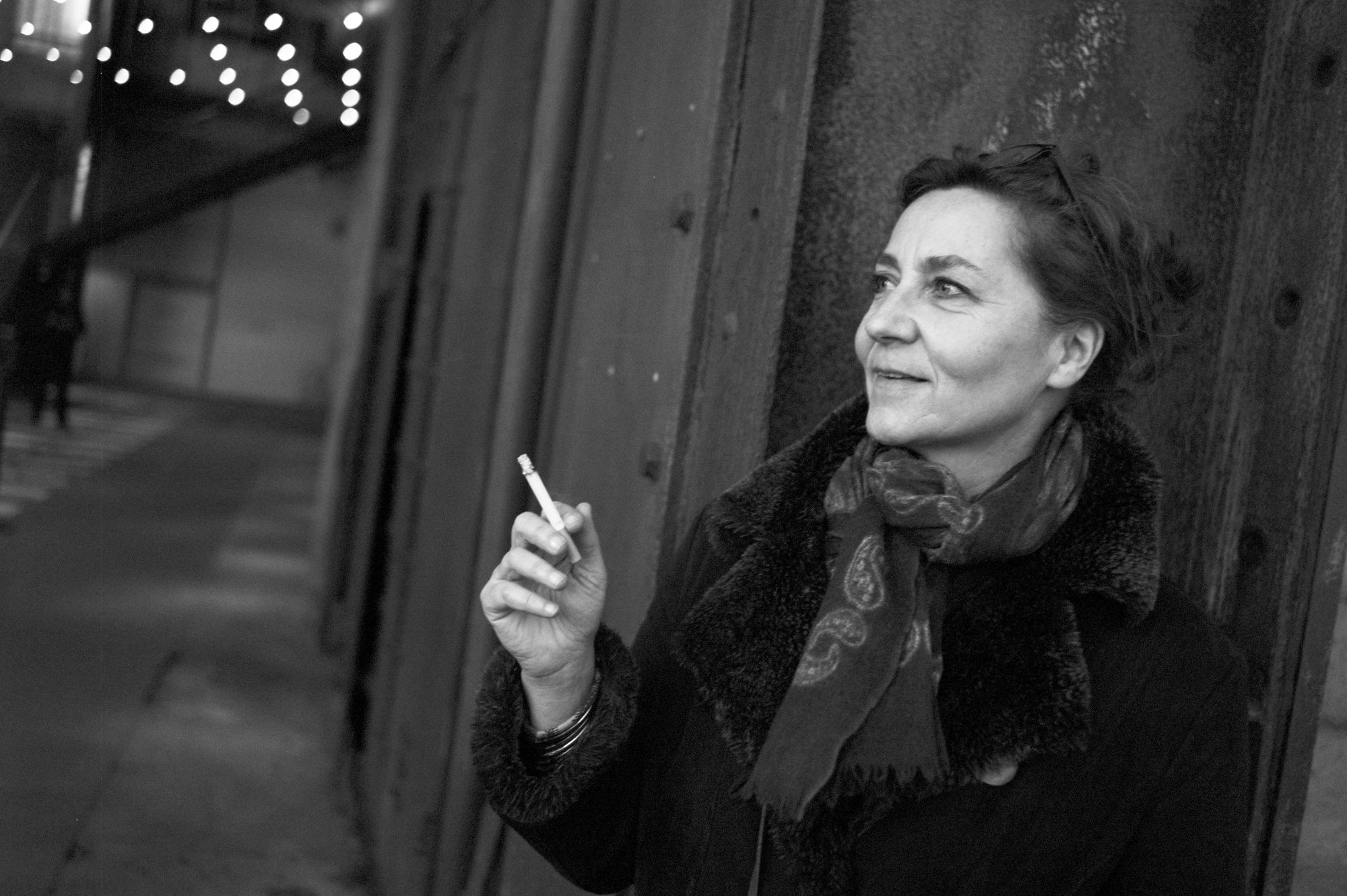 Anne Serres blickt in die Ferne. In der Hand hält sie eine Zigarette.
