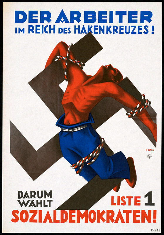 Auf dem Plakat steht: „Der Arbeiter im Reich des Hakenkreuzes“. Zu sehen ist ein roter Arbeiter, der an ein Hakenkreuz gefesselt ist.