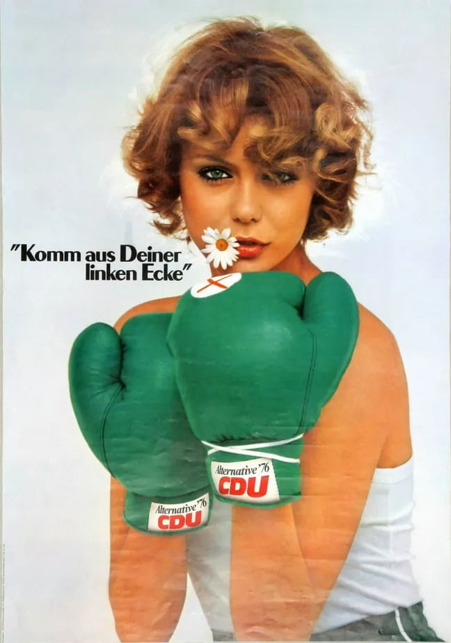 Eine Frau mit Gänseblümchen im Mundwinkel und grünen Fausthandschuhen. Neben ihrem Gesicht steht "Komm aus Deiner linken Ecke".