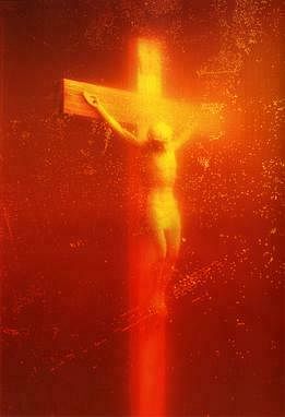 Ein Kreuz mit Jesus, das in rotes Licht getaucht ist. Außerdem sind Spritzer einer Flüssigkeit zu sehen.