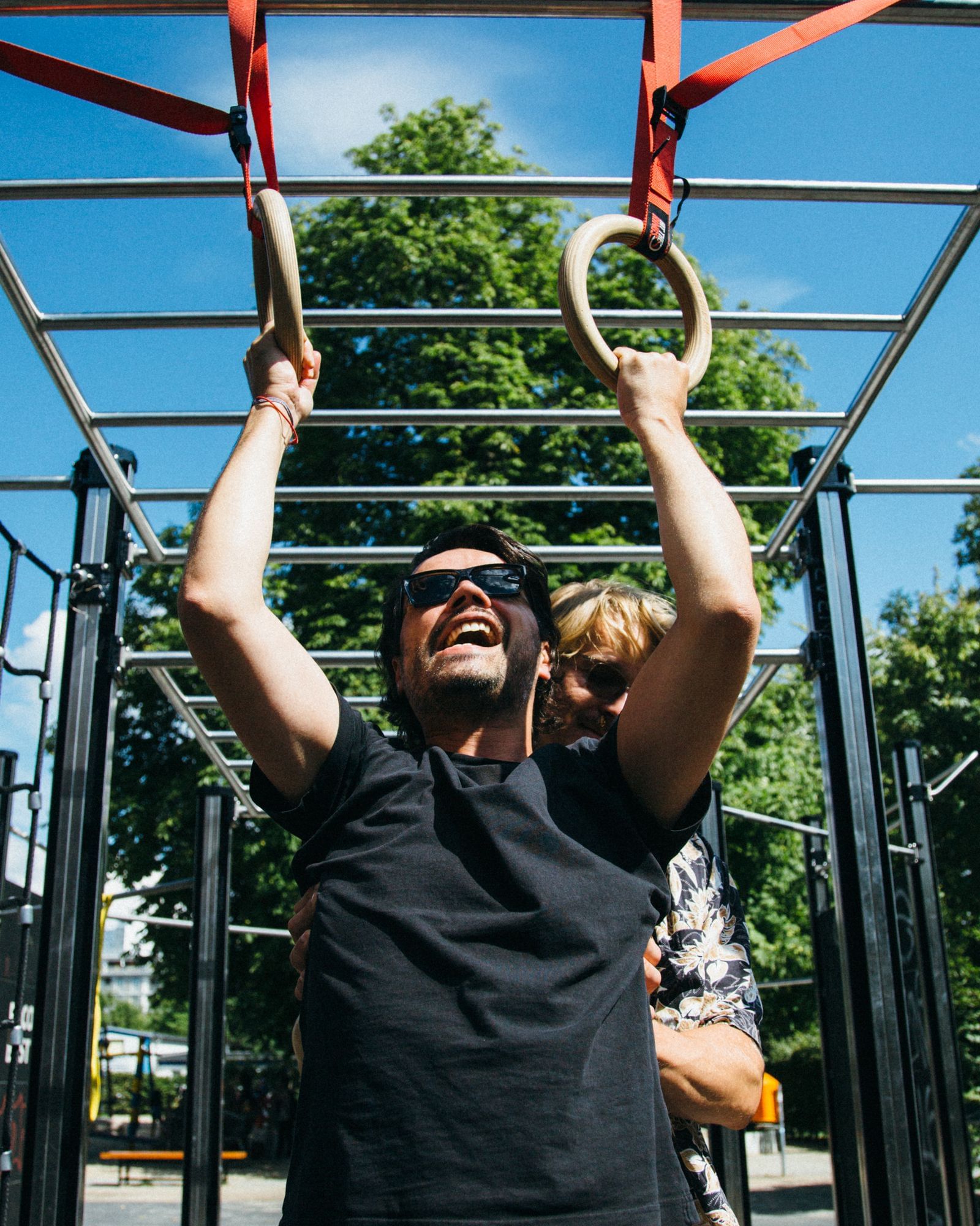 Ein Mann hängt an zwei Gymnastikringen und versucht einen Klimmzug zu machen