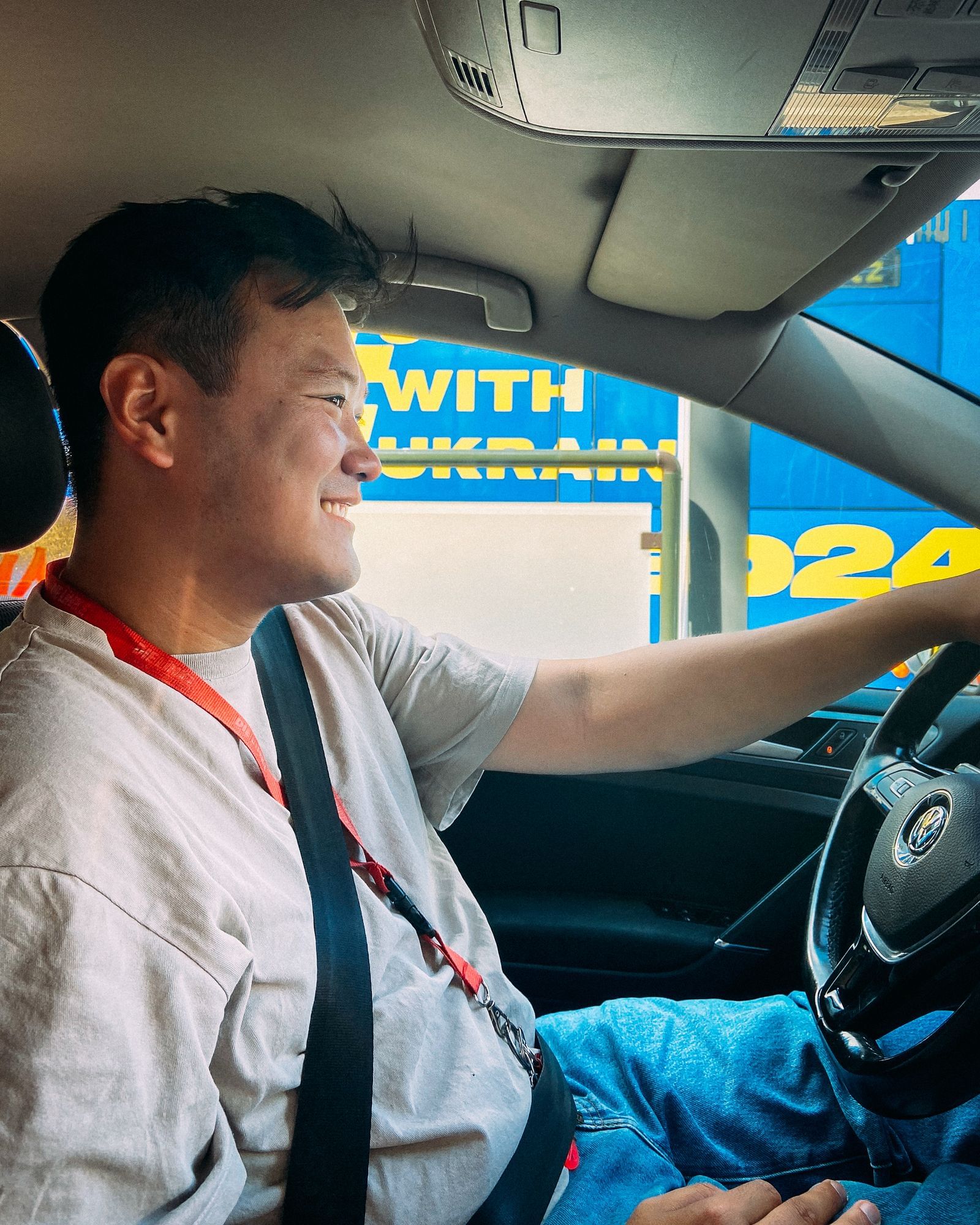 Nam Duy Nguyen sitzt im Auto am Steuer. Er lächelt.