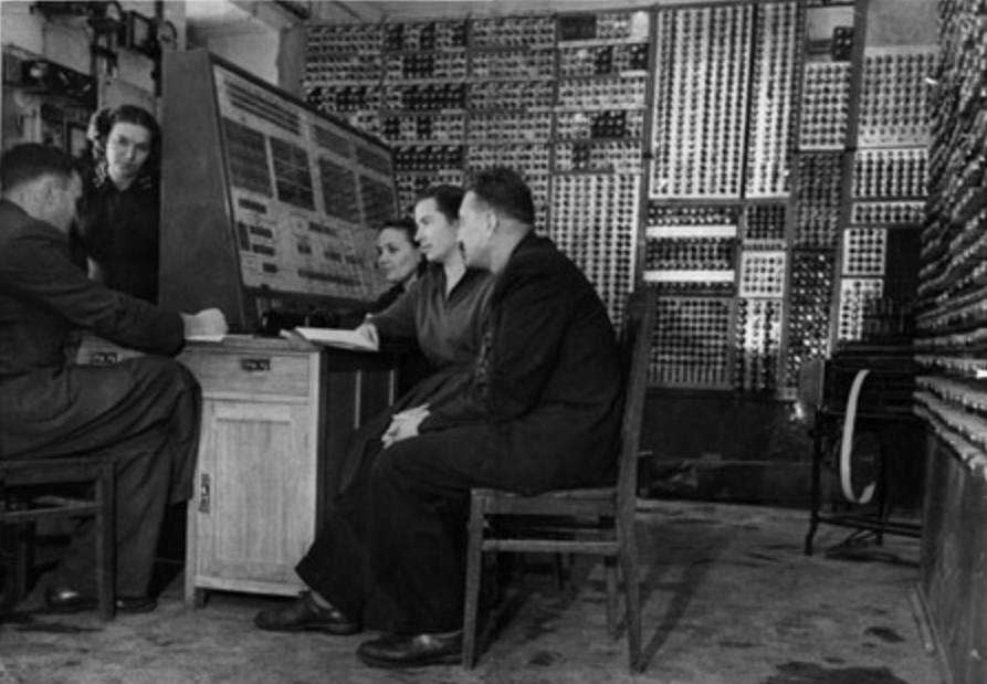 Mehrere Personen sitzen an einem Computer, der einen ganzen Raum füllt.