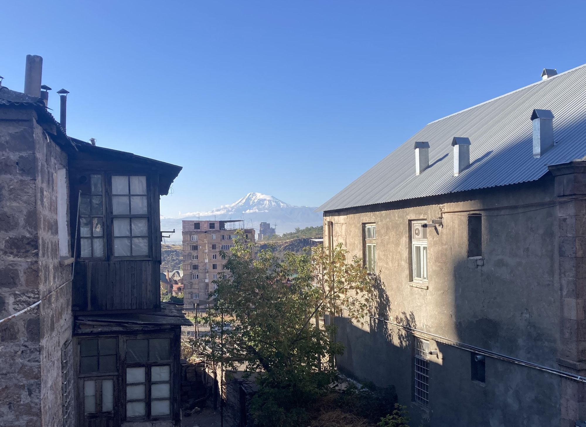 Auf dem Foto sind zwei Gebäude zu sehen, im Hintergrund ein schneebedeckter Berg.