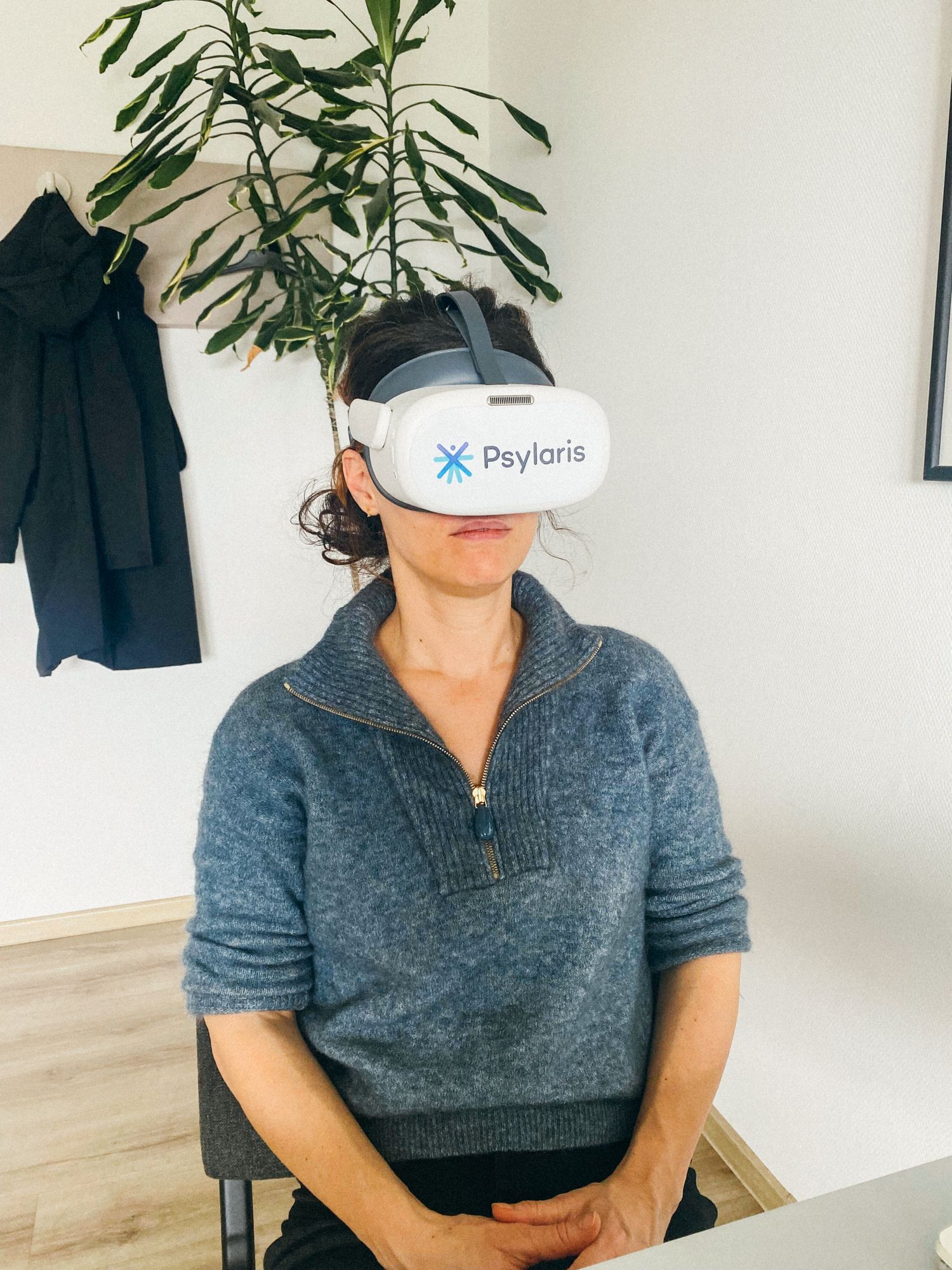 Die Autorin sitzt am Tisch und trägt eine VR-Bille. Sie ist weiß und bedeckt den größten Teil ihres Gesichts.