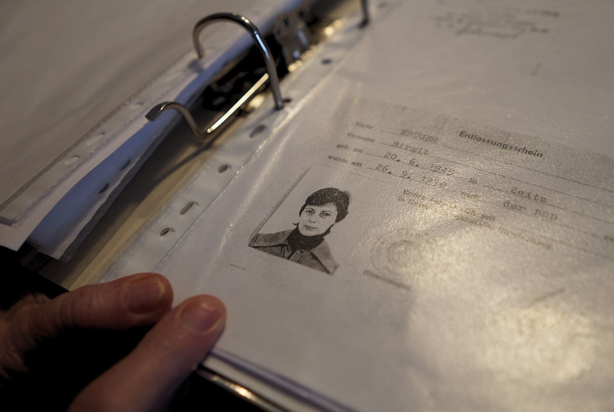 Man sieht ein Stück Papier in einer Glassichtfolie mit der Überschrift "Entlassungsschein". Darauf ist ein Foto von Birgit Krüger.