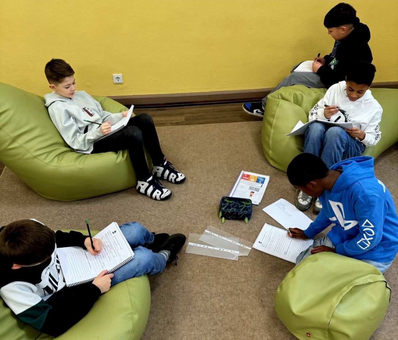 Kinder sitzen auf den Sitzsäcken im sogenannten Differenzierungsraum und arbeiten an ihren Heften.