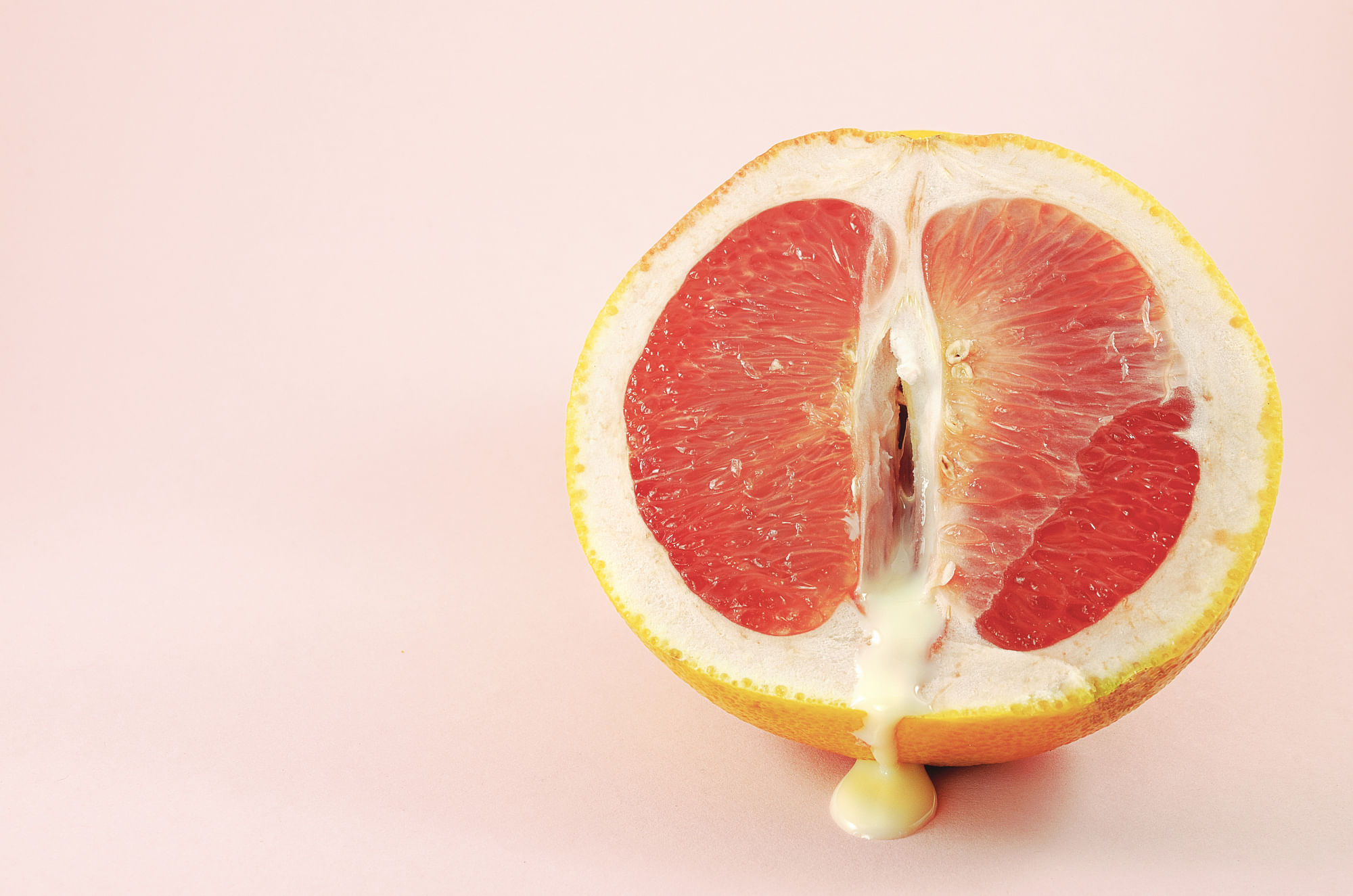 Eine halbierte Grapefruit, aus der eine weiße Sauce läuft.