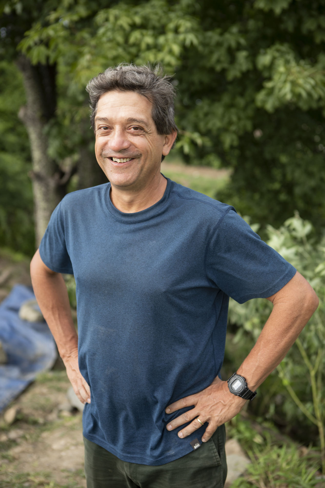 Eduardo Neves, mit blauem T-Shirt, lächelt mit angewinkelten Armen in die Kamera.