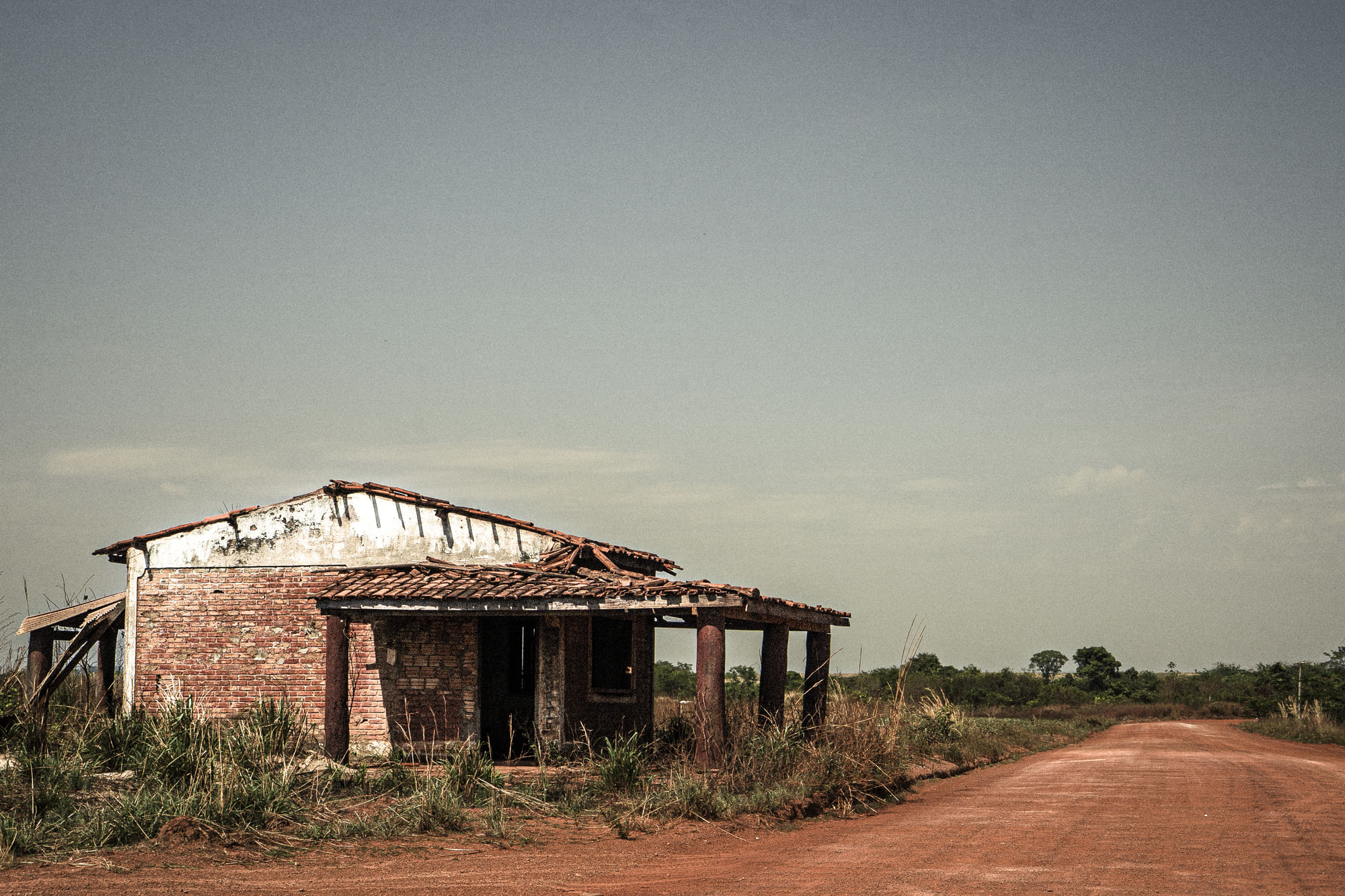 Ein eingeallenes Haus steht neben einer Schotterstraße.