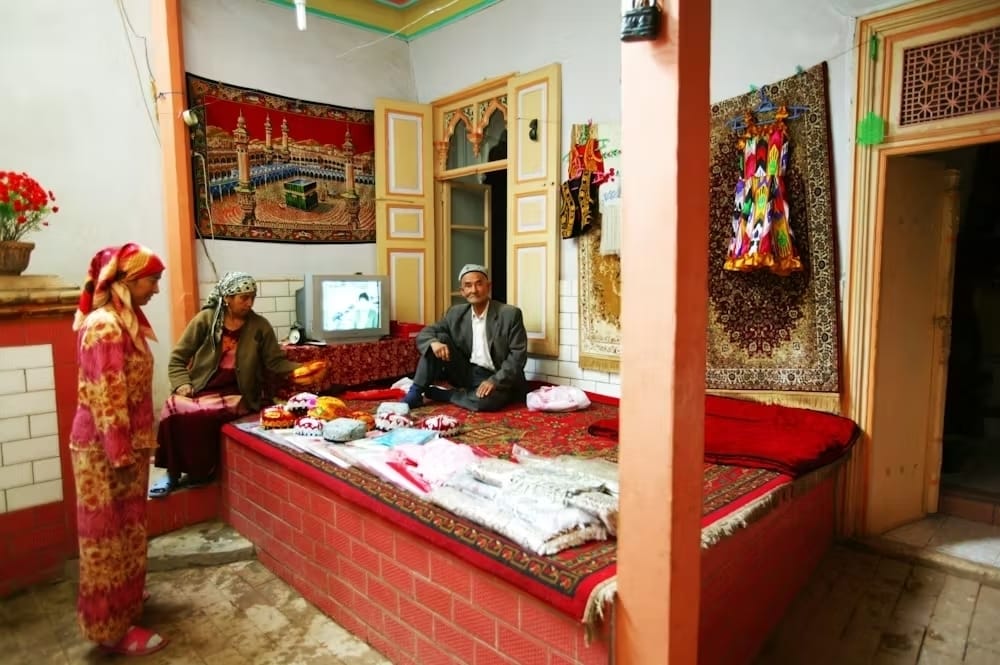 Im Westen Chinas sitzt eine uigurische Familie auf ihrem „Kang“.  